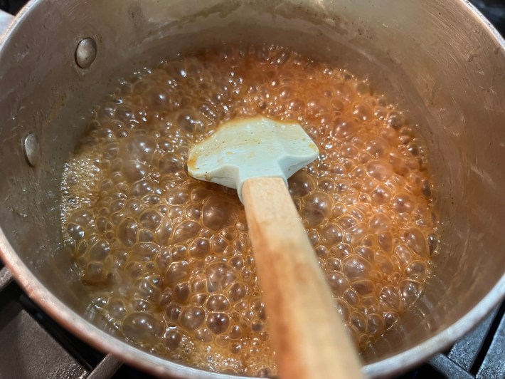 Caramel sauce reducing in a saucepan.
