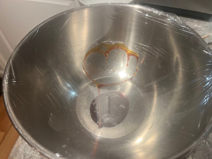 A hole burned through plastic wrap stretched across a bowl.