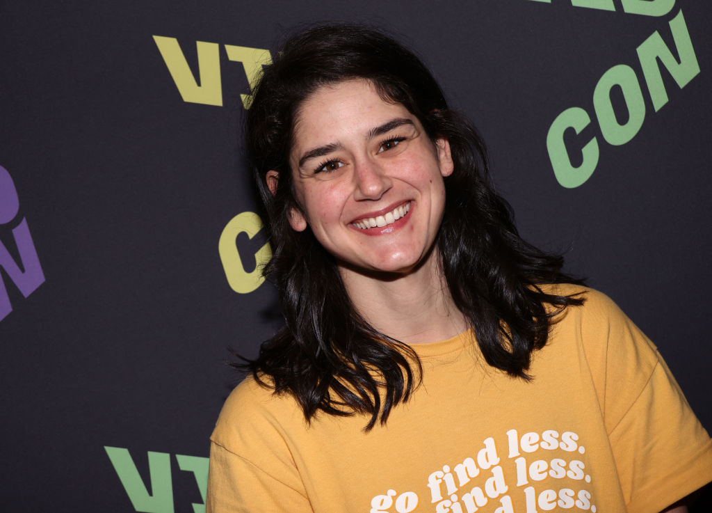 elyse myers in a yellow shirt smiles at the camera