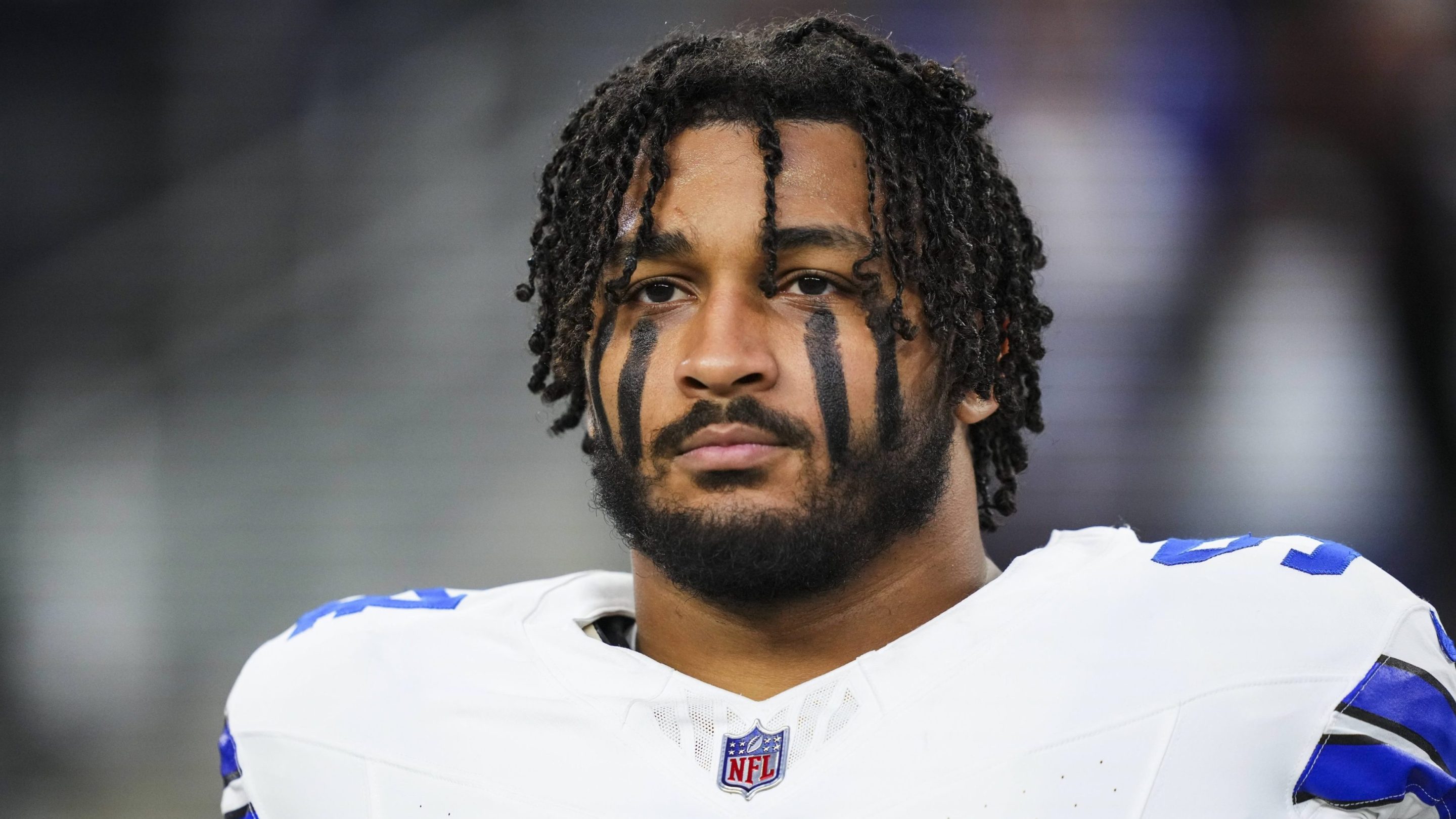 Marshawn Kneeland #94 of the Dallas Cowboys looks on from the sideline during the national anthem prior to an NFL football game against the Tampa Bay Buccaneers at AT&T Stadium on December 22, 2024 in Arlington, Texas. He is wearing his Cowboys jersey and his helmet is off.