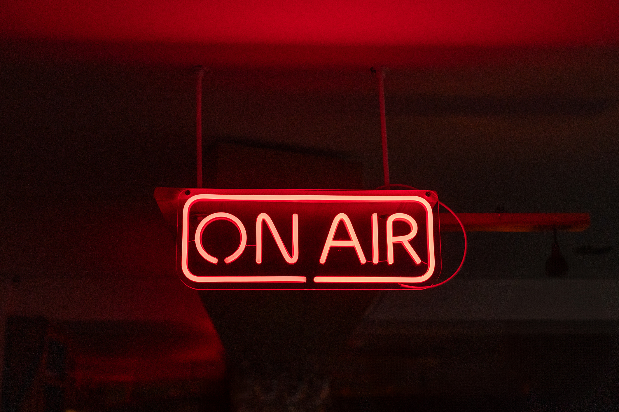Neon red "on air" sign in a dark room