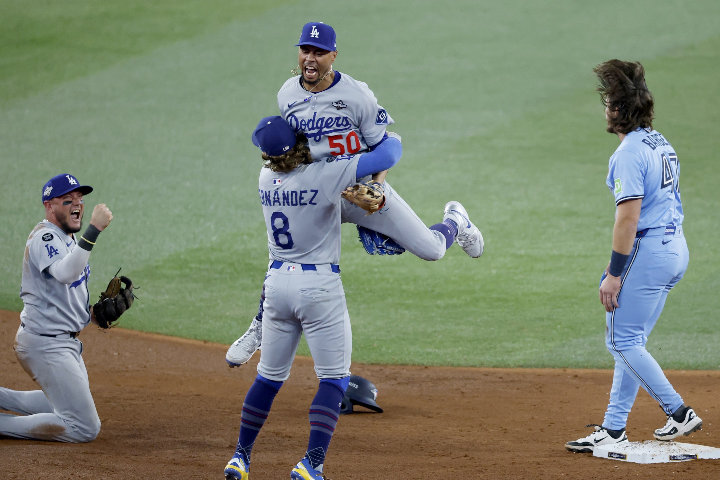 Toronto, Ontario, Canada October 31, 2025: Los Angeles Dodgers shortstop Mookie Betts (50) leaps to Los Angeles Dodgers first baseman Enrique Hernandez (8) after the final out while Toronto Blue Jays third baseman Addison Barger (47) is out at second in the ninth inning and Los Angeles Dodgers Miguel Rojas celebrates during game six of the World Series between the Los Angeles Dodgers and the Toronto Blue Jays at Roger Centre on Friday, October 31, 2025 in Los Angeles, CA.(Gina Ferazzi / Los Angeles Times via Getty Images)