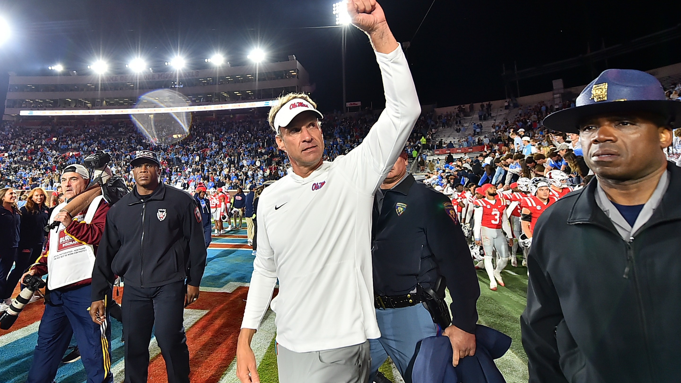 Ole Miss head coach Lane Kiffin stands on the field with a raised fist.