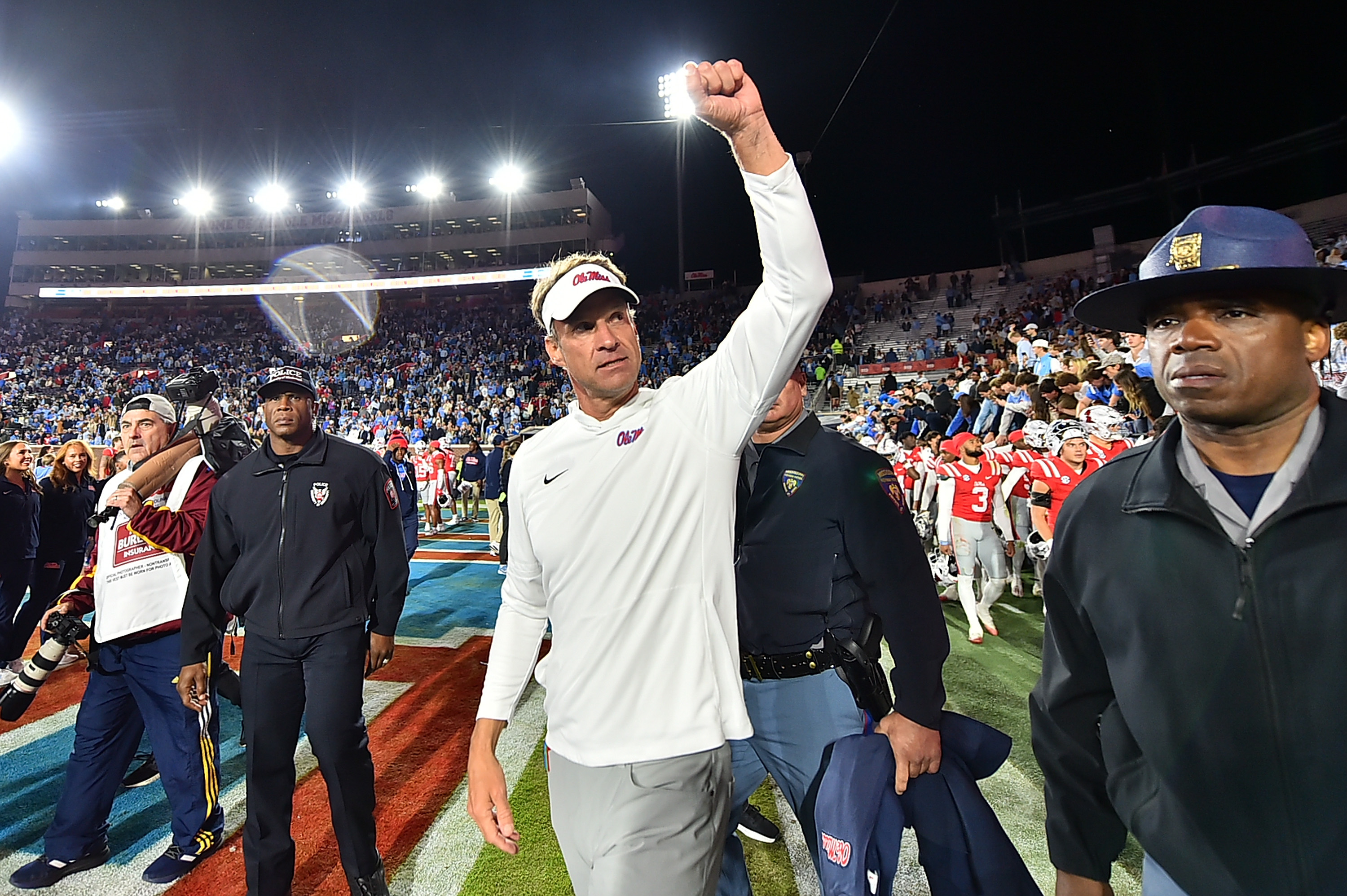 Ole Miss head coach Lane Kiffin stands on the field with a raised fist.