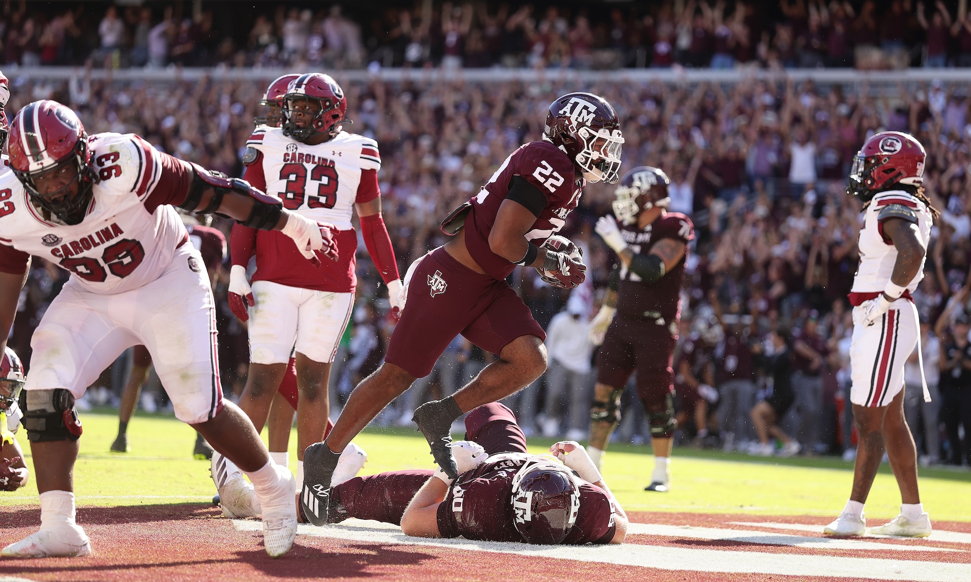 A bunch of South Carolina Gamecocks stand around looking dumb and confused as a Texas A&M guy celebrates a touchdown.