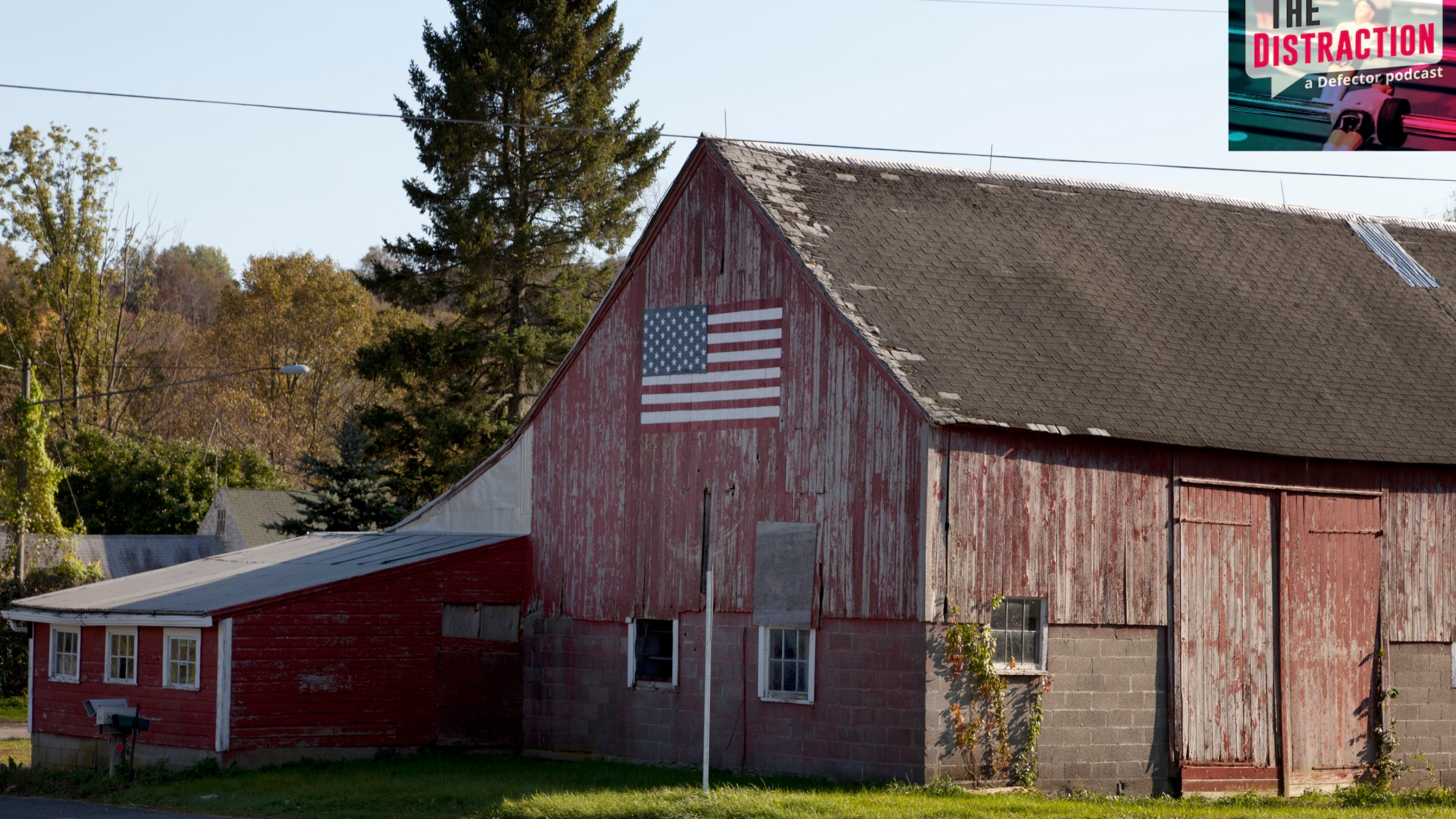 A barn near Litchfield, Connecticut. It is painted in a faded red, and there's an American flag painted on the front of it. The Distraction logo is at upper right.