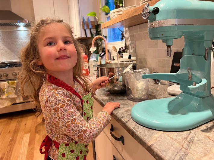 My child spoons whipped cream into a bag.