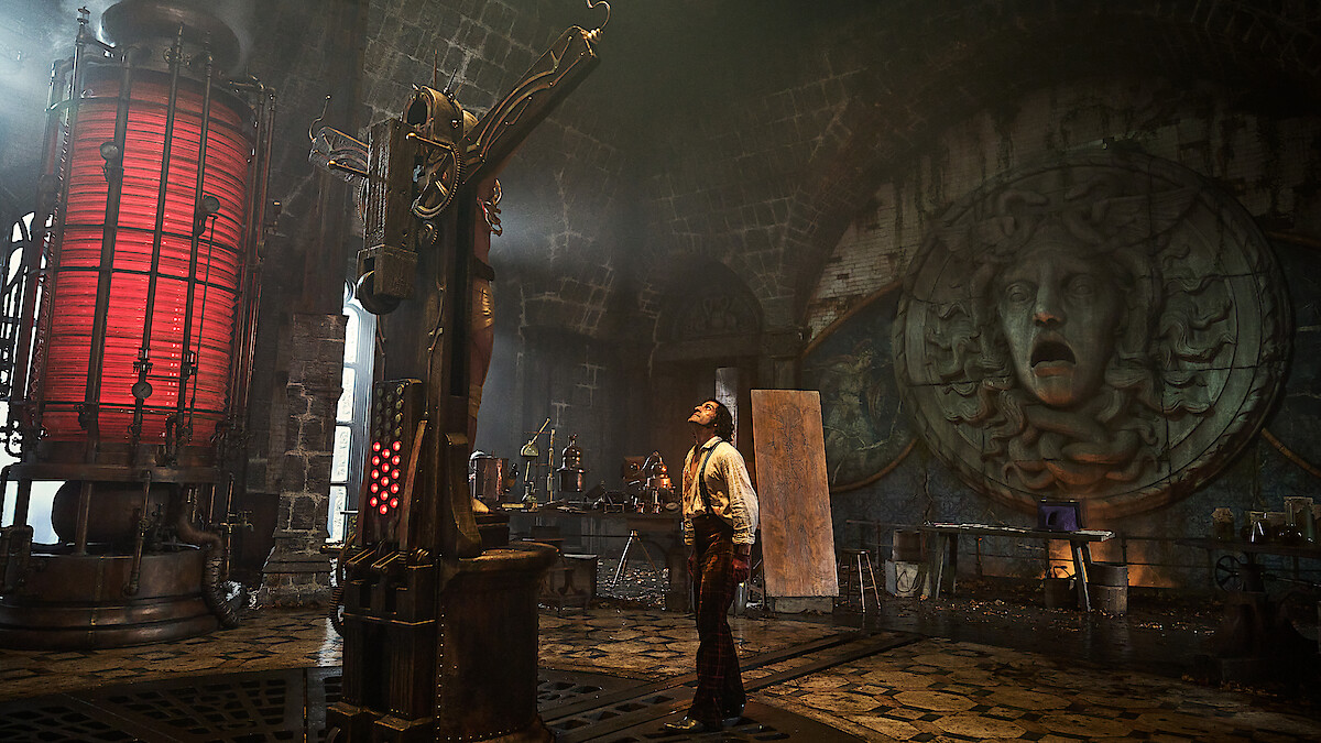 oscar issac as frankenstein gazes up at his creature on a cross