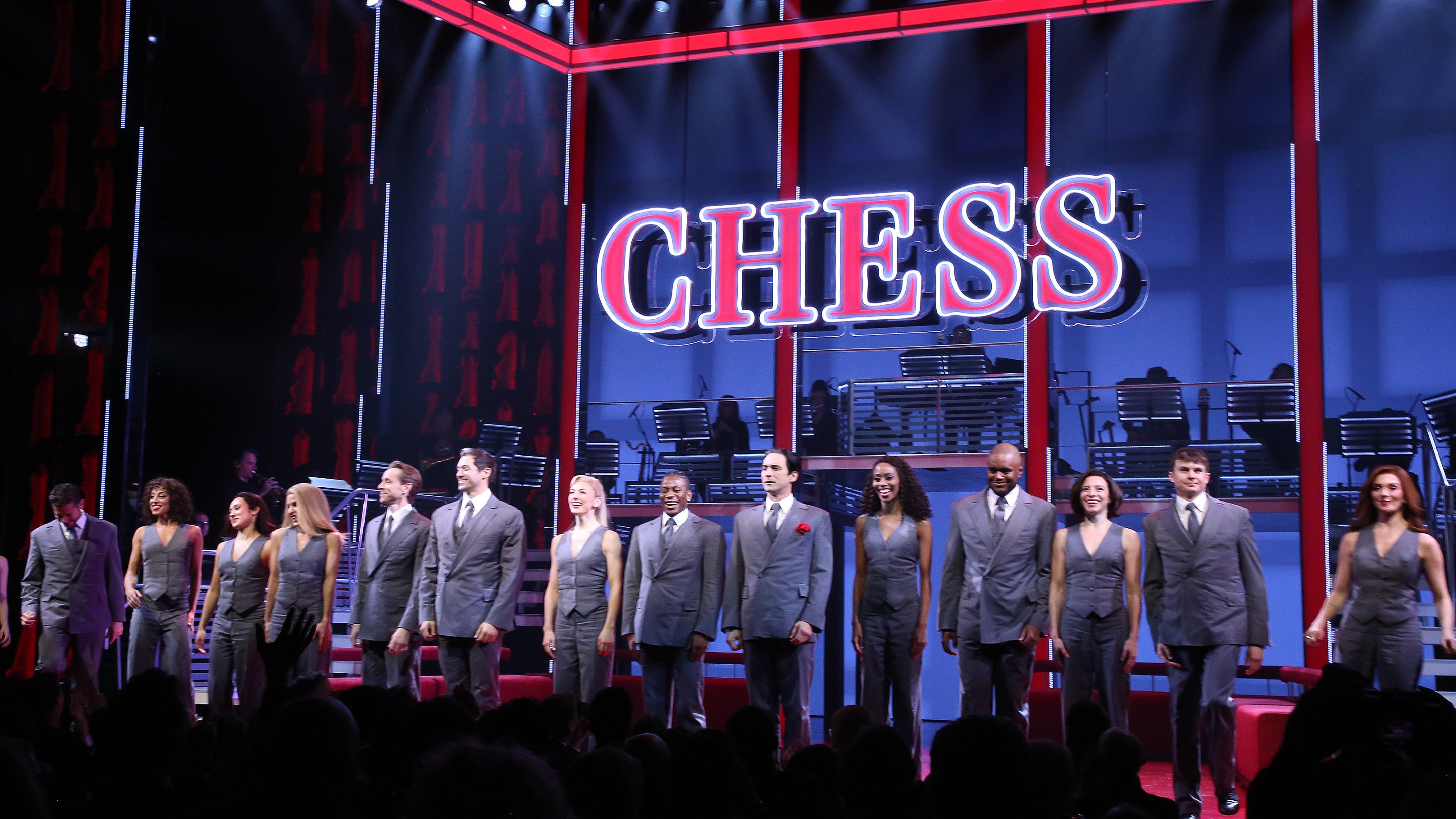 a photo of the set of the broadway musical Chess, with a sign that says CHESS, and the chorus standing for bows in front of it