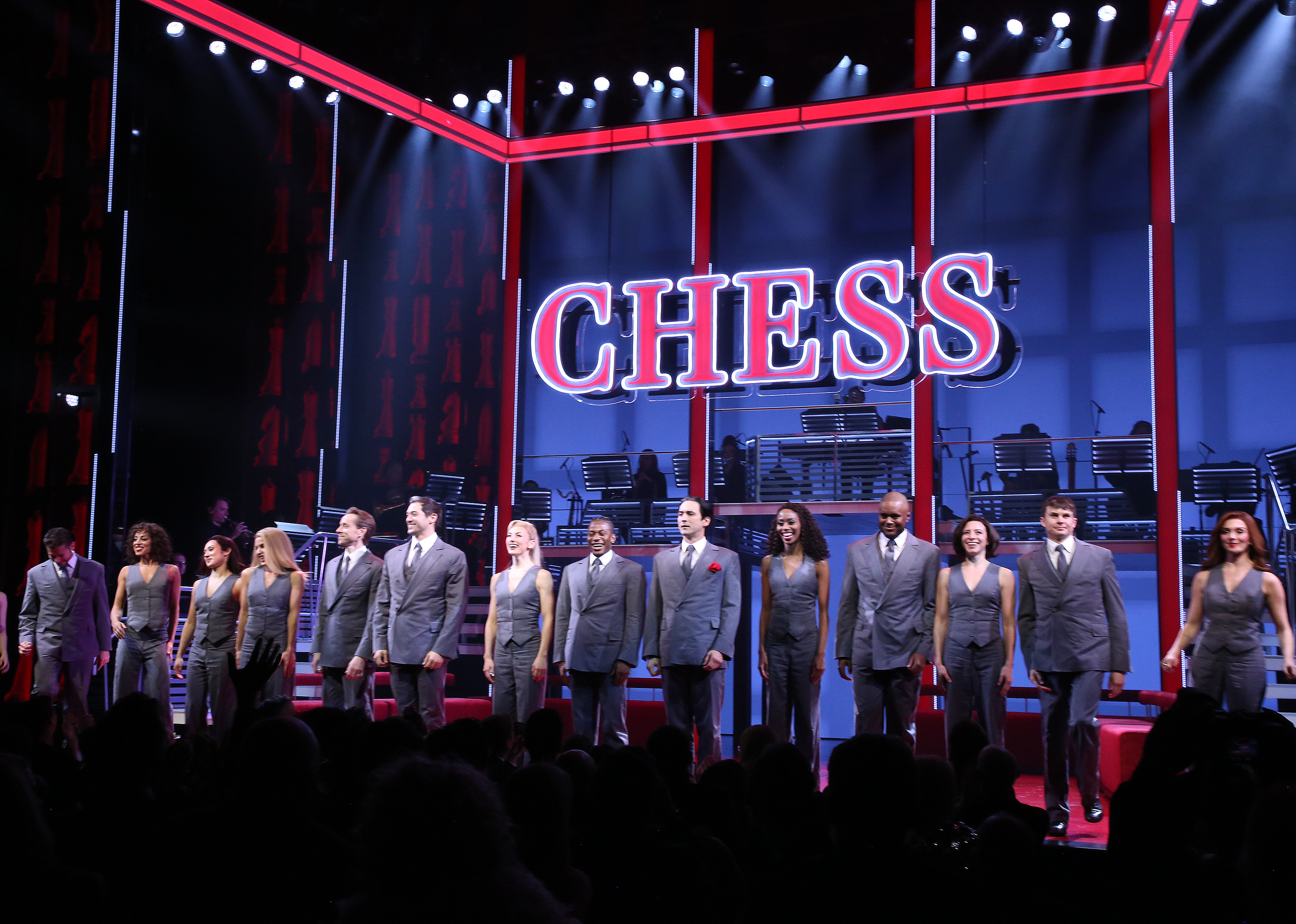 a photo of the set of the broadway musical Chess, with a sign that says CHESS, and the chorus standing for bows in front of it