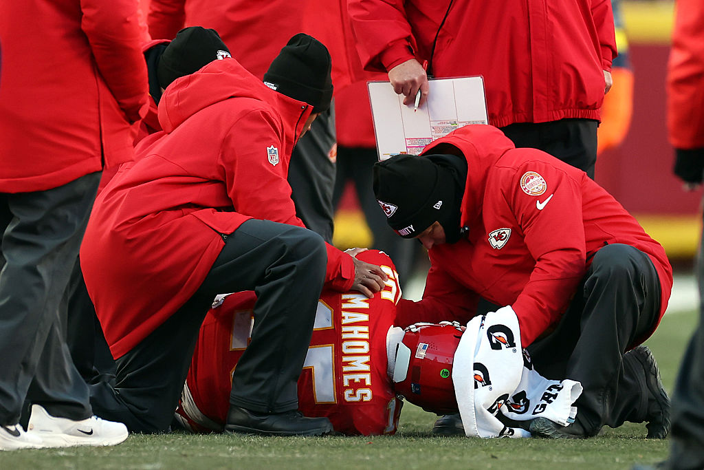 KANSAS CITY, MISSOURI - DECEMBER 14: Patrick Mahomes #15 of the Kansas City Chiefs lays on the ground after sustaining an injury during the fourth quarter against the Los Angeles Chargers at Arrowhead Stadium on December 14, 2025 in Kansas City, Missouri.