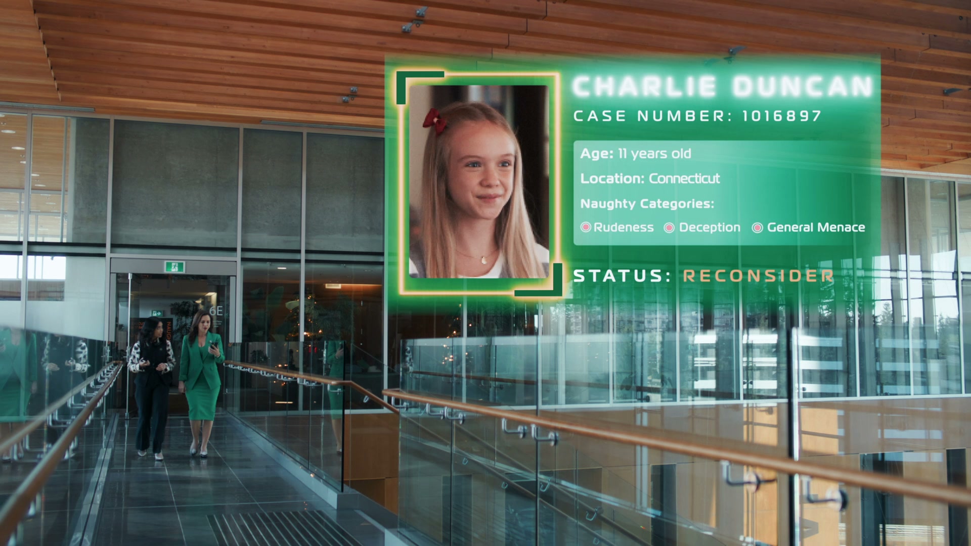 Corporate office, maybe mid-2010s style. Two women are walking in the background, and in front of them is a digital display about Charlie Duncan, case number 1016897, and how she's rude, deceptive, and a general menace.