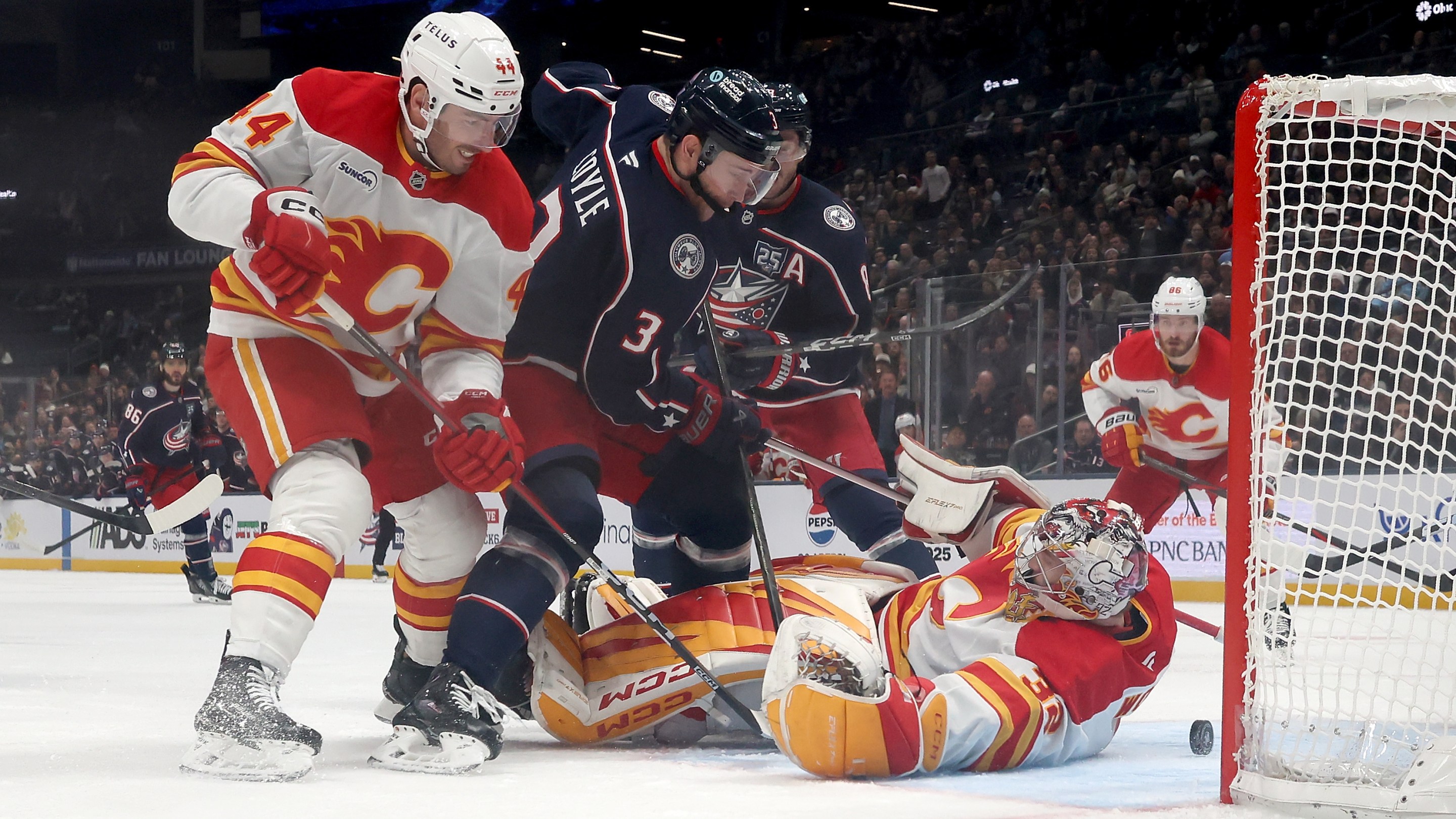 Dustin Wolf #32 of the Calgary Flames looses control of the puck as Joel Hanley #44 defends against Charlie Coyle #3 of the Columbus Blue Jackets during the third period of the game
