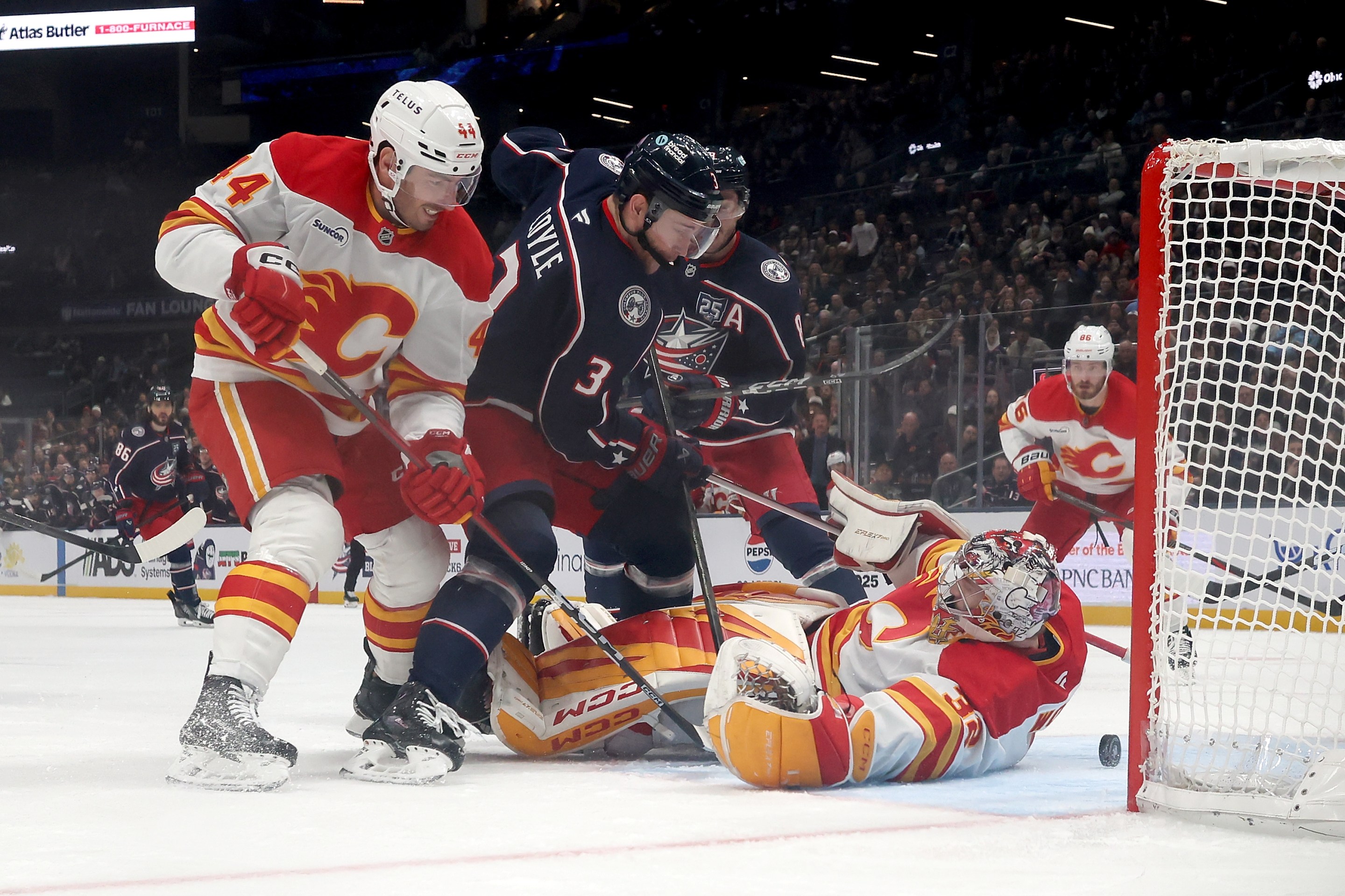 Dustin Wolf #32 of the Calgary Flames looses control of the puck as Joel Hanley #44 defends against Charlie Coyle #3 of the Columbus Blue Jackets during the third period of the game