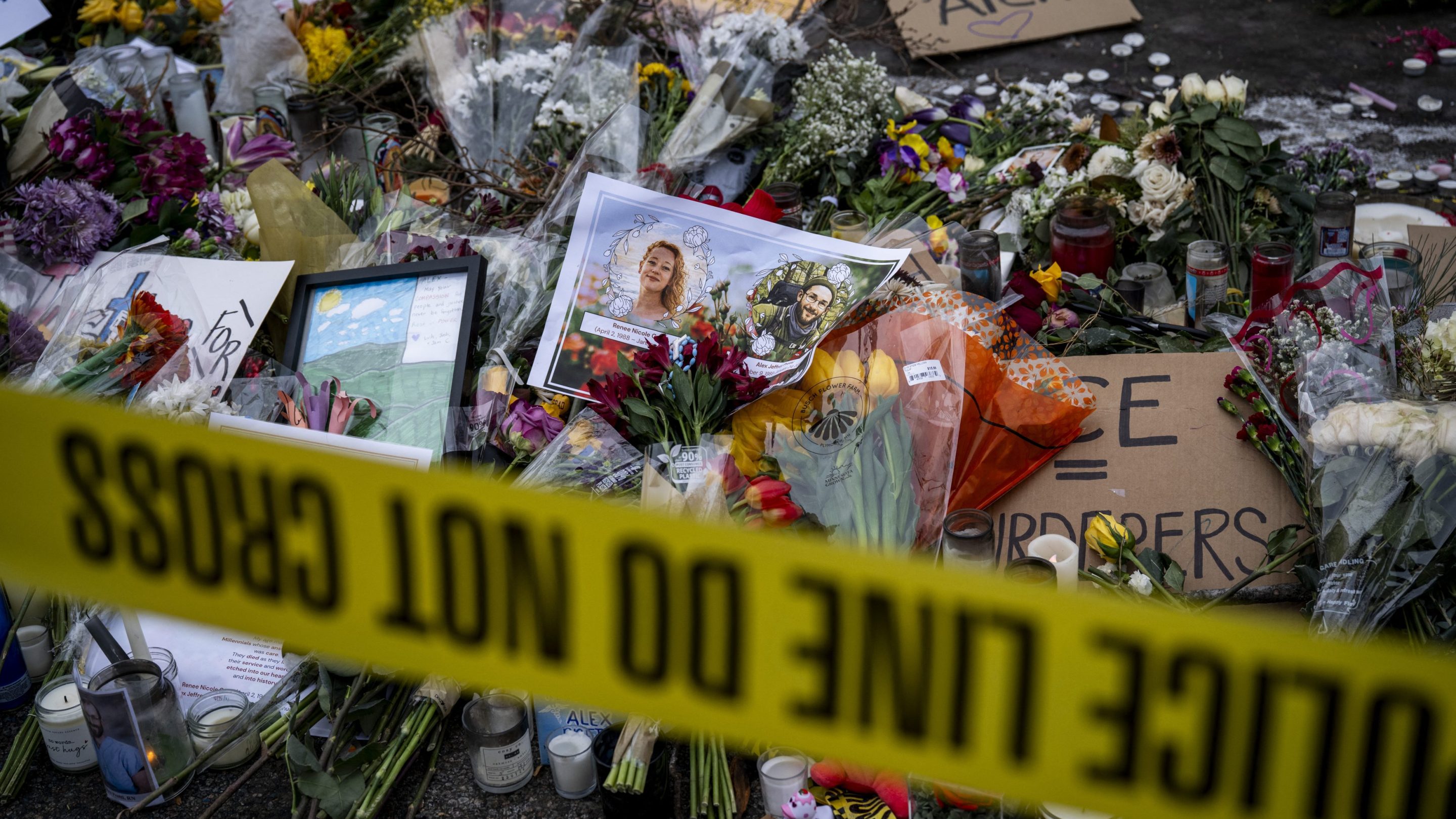 Photos of Nicole Good (L) and Alex Pretti are placed among flowers at a makeshift memorial in the area where Pretti was shot and killed by Federal immigration agents in Minneapolis, Minnesota