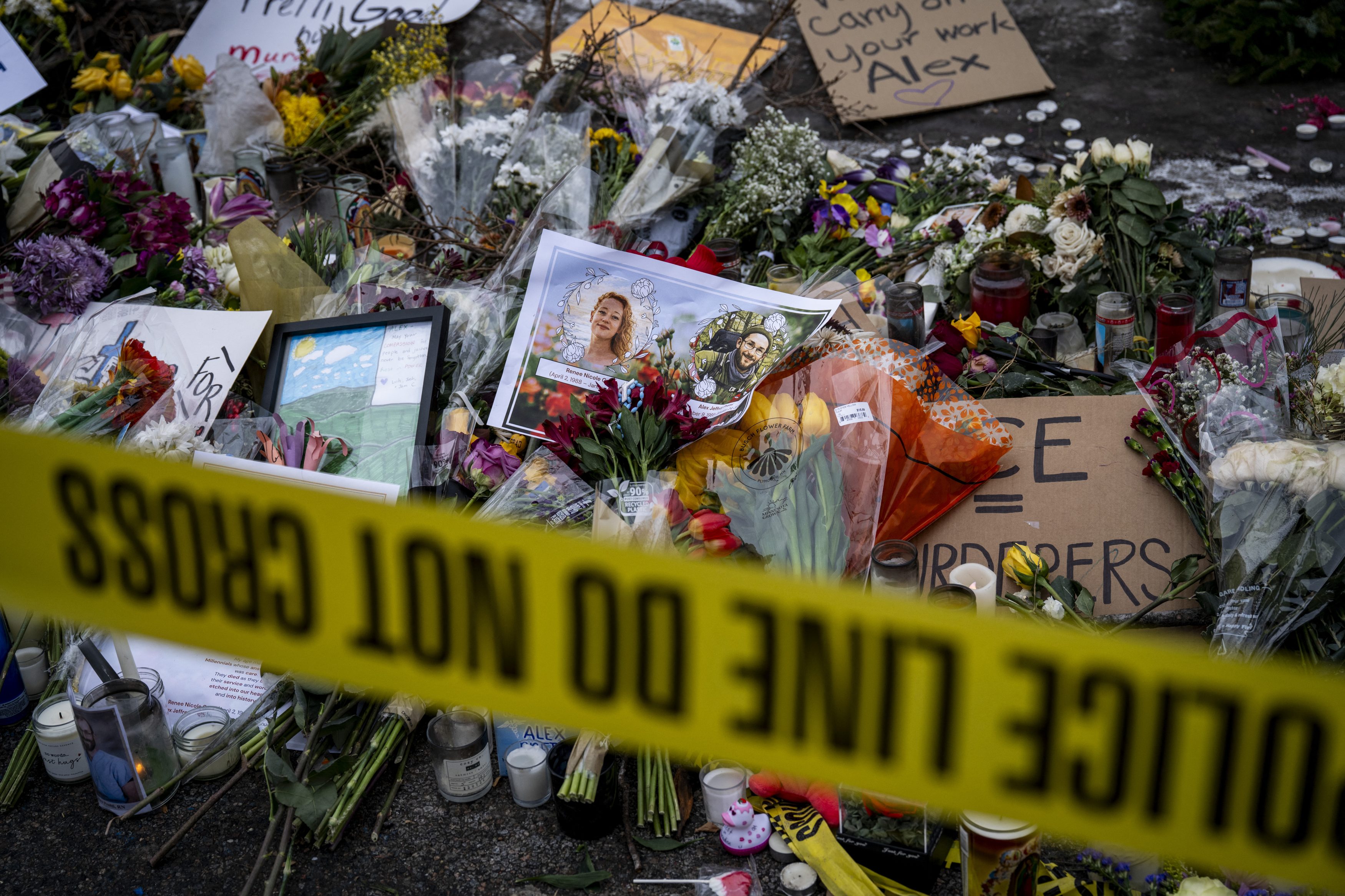 Photos of Nicole Good (L) and Alex Pretti are placed among flowers at a makeshift memorial in the area where Pretti was shot and killed by Federal immigration agents in Minneapolis, Minnesota