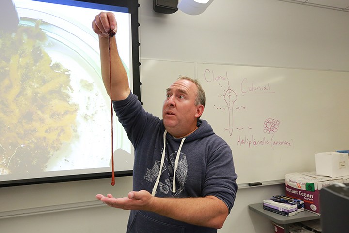 jon allen holds a worm up in front of a class
