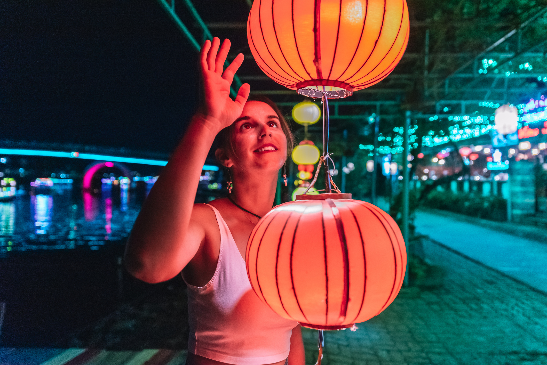 Portrait of a beautiful young woman smiling and touching a lantern that illuminates her face.