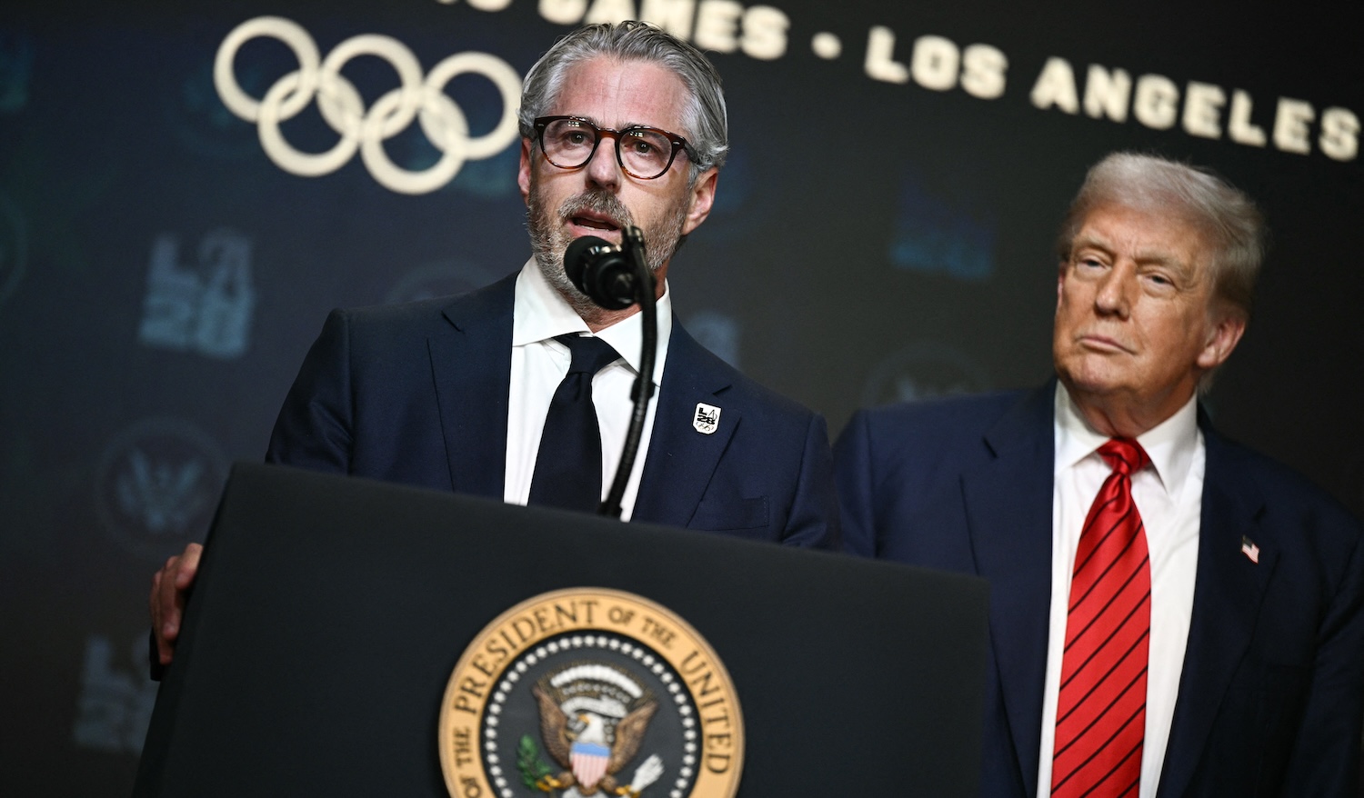 US President Donald Trump (R) looks on as LA 2028 Chairman Casey Wasserman (L) speaks during an event on creating a White House 2028 Olympics task force in the South Court Auditorium of the White House in Washington, DC, on August 5, 2025. The 2028 Summer Olympics will be held in Los Angeles. (Photo by Brendan SMIALOWSKI / AFP)