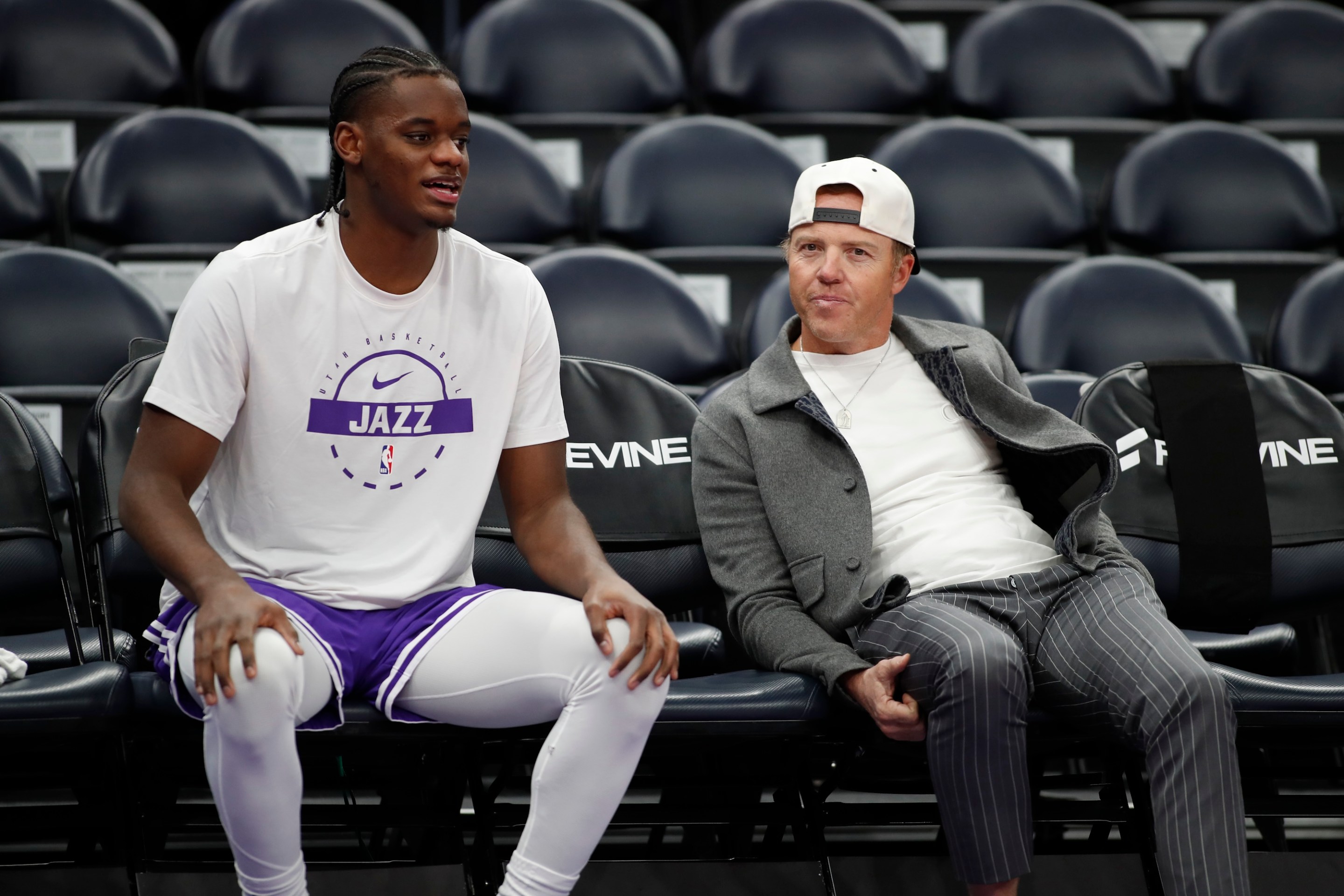 Taylor Hendricks of the Utah Jazz talks with team owner Ryan Smith during warmups before their game against the Dallas Mavericks at the Delta Center on January 8, 2026. Smith has a backwards baseball cap on, as always.