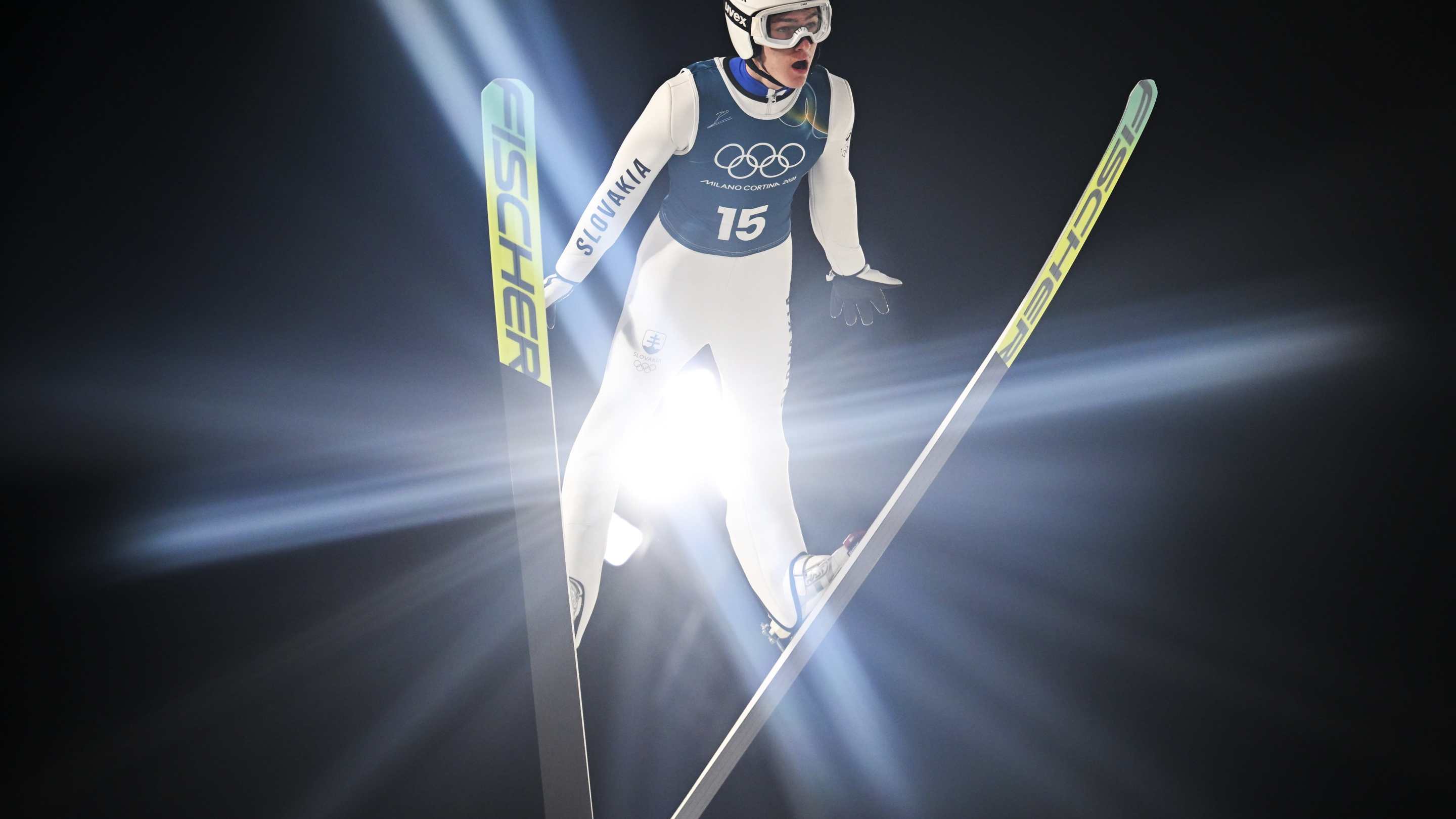 a bright light shines through the space between a ski jumper's legs