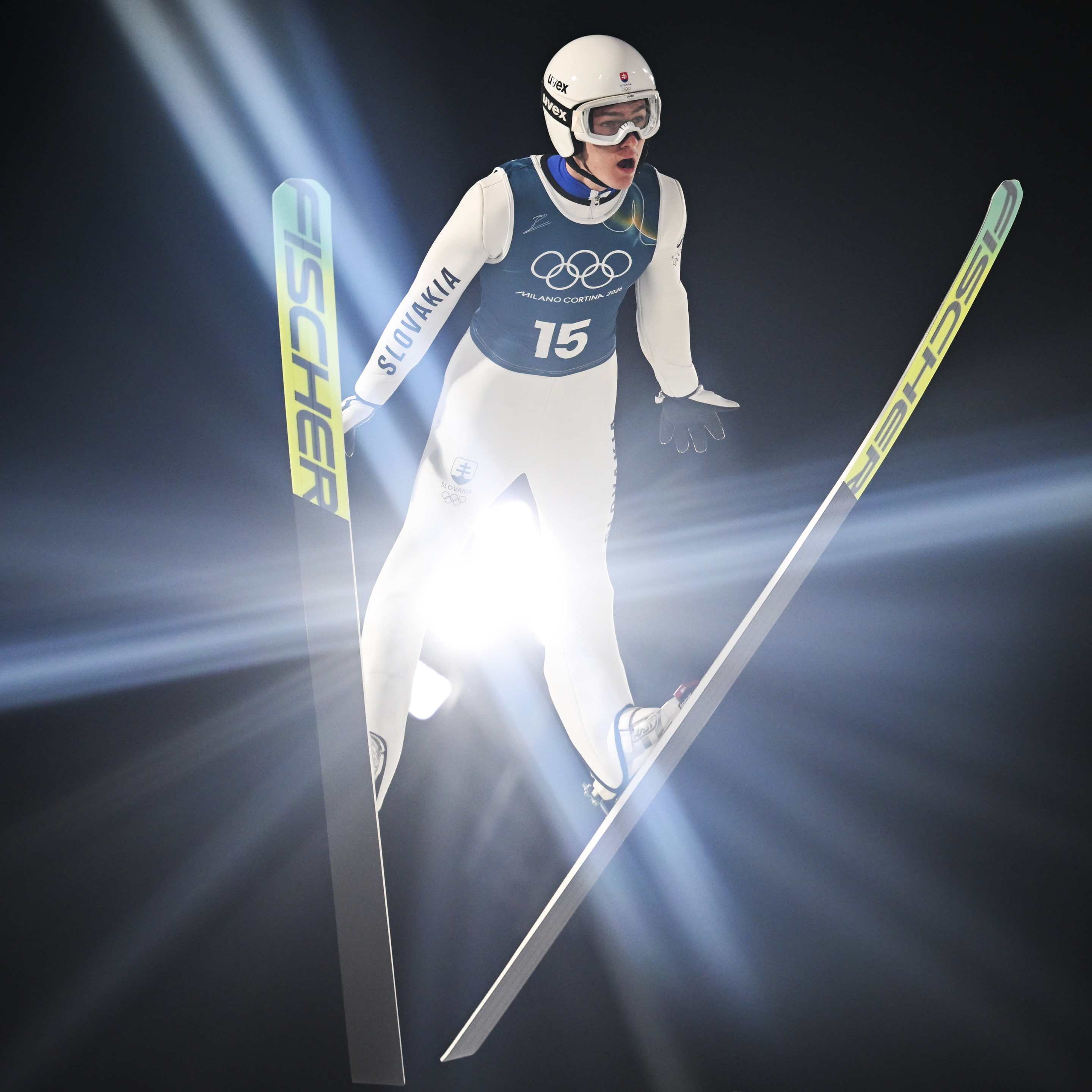 a bright light shines through the space between a ski jumper's legs