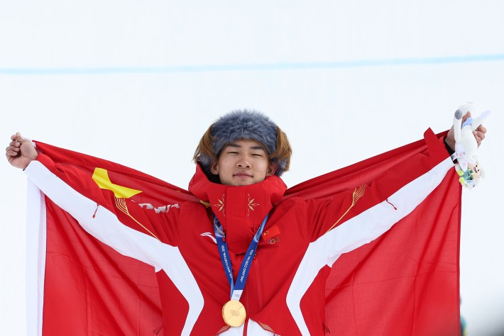 Gold medalist Su Yiming of Team China celebrates on the podium during the medal ceremony for the Men's Snowboard Slopestyle on day twelve of the Milano Cortina 2026 Winter Olympics
