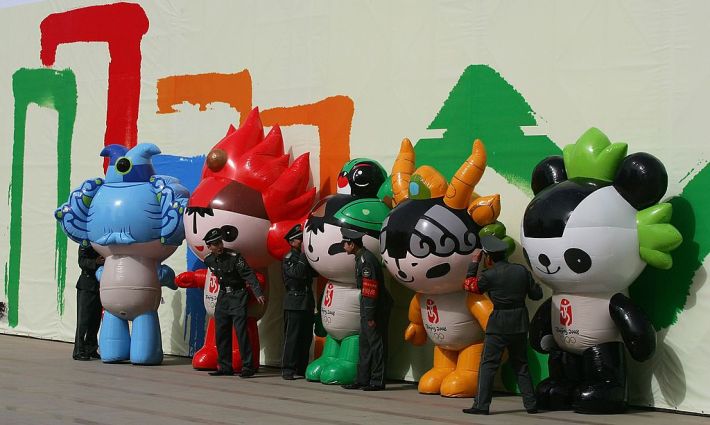 the five mascots of the Beijing Olympic games standing in front of a wall with security guards