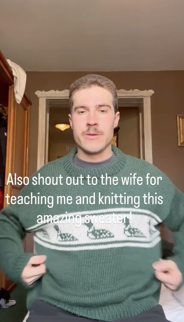 An image of Adam Runnalls wearing a green sweater with some ducks on it, taking from his Instagram account. The text over it reads "Also shout out to the wife for teaching me and knitting this amazing sweater."