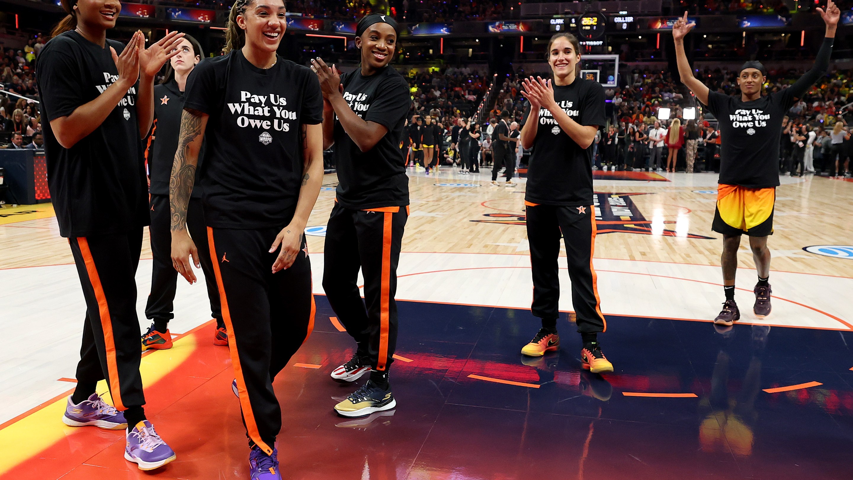 Kiki Iriafen #44 of the Washington Mystics, Gabby Williams #5 of the Seattle Storm, Jackie Young #0 of the Las Vegas Aces, Sonia Citron #2 of the Washington Mystics and Brittney Sykes #15 of the Washington Mystics wear shirts saying "Pay us what you owe us" prior to the 2025 AT&amp;T WNBA All-Star Game at Gainbridge Fieldhouse on July 19, 2025 in Indianapolis, Indiana.