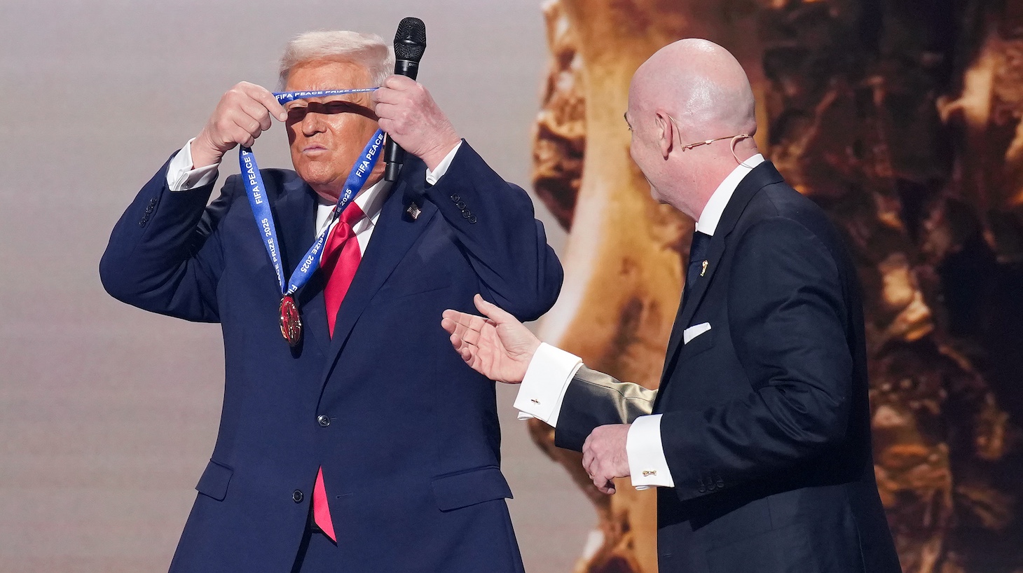 U.S. President Donald Trump places the FIFA Peace Prize around his neck after receiving it from FIFA President Gianni Infantino (R) at the FIFA World Cup 2026 Official Draw at the John F. Kennedy Center for the Performing Arts December 05, 2025 in Washington, DC.