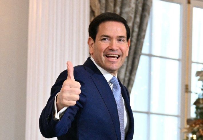 An image of Marco Rubio giving a weird thumbs up and smiling with his mouth open.