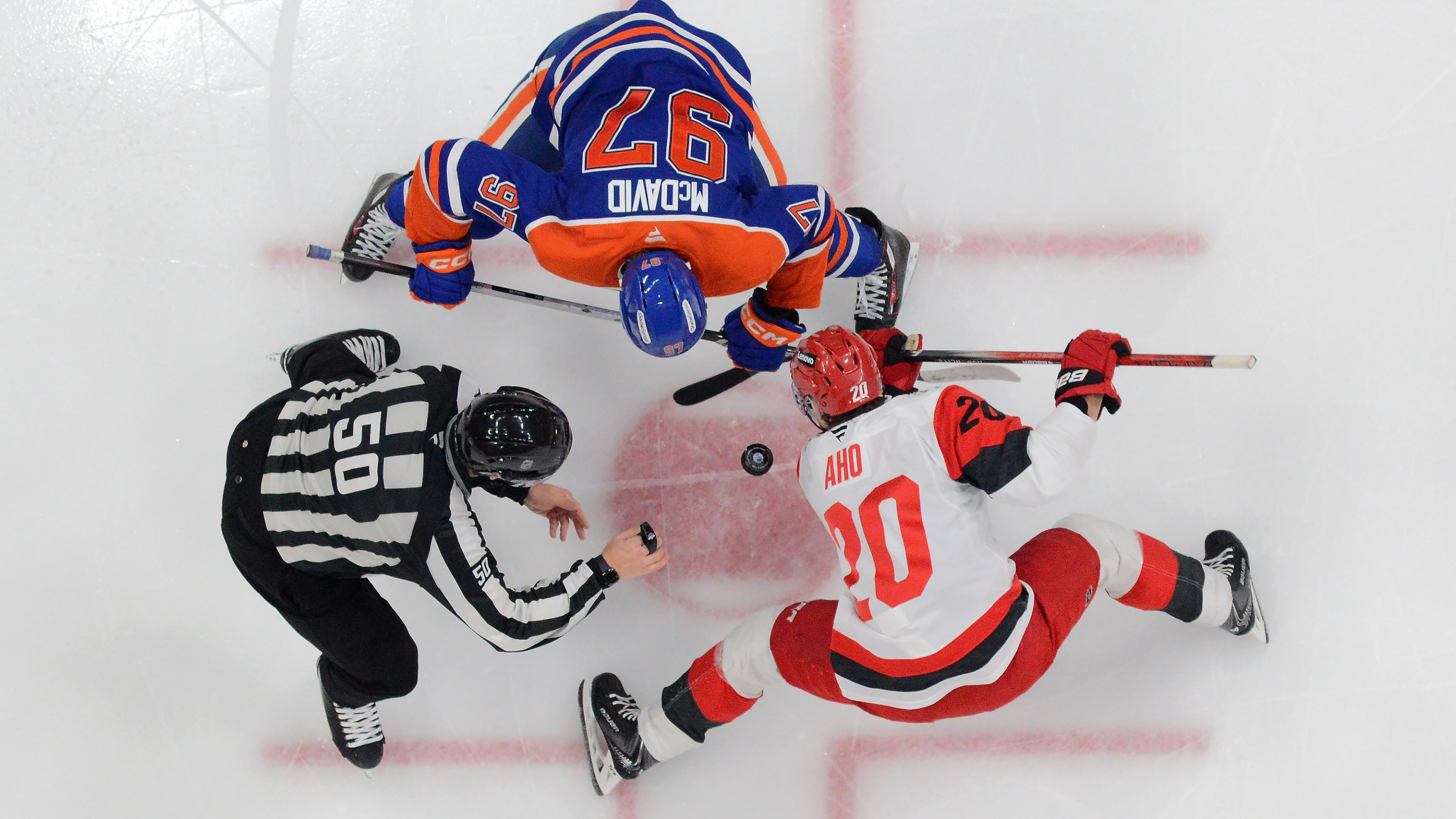 Connor McDavid #97 of the Edmonton Oilers faces off against Sebastian Aho