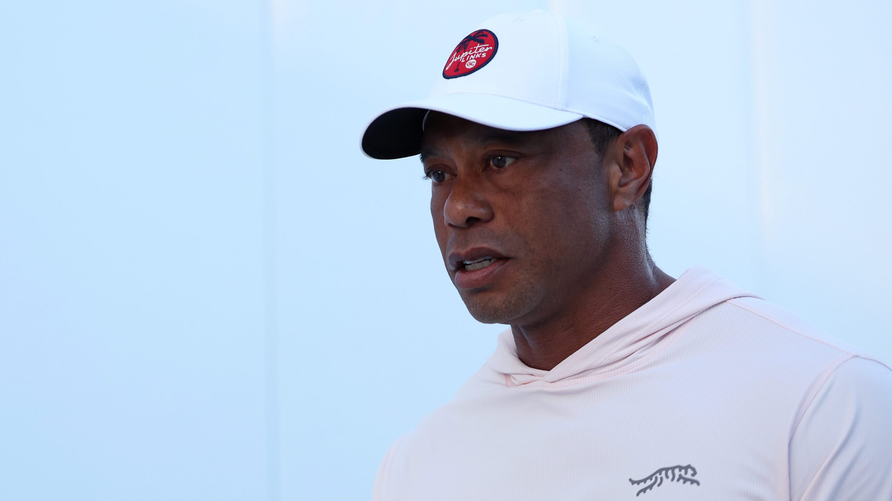 Tiger Woods of Jupiter Links Golf Club arrives before the match against the Los Angeles Golf Club at SoFi Center on March 23, 2026 in Palm Beach Gardens, Florida. He's wearing a white hoodie and a white baseball hat.
