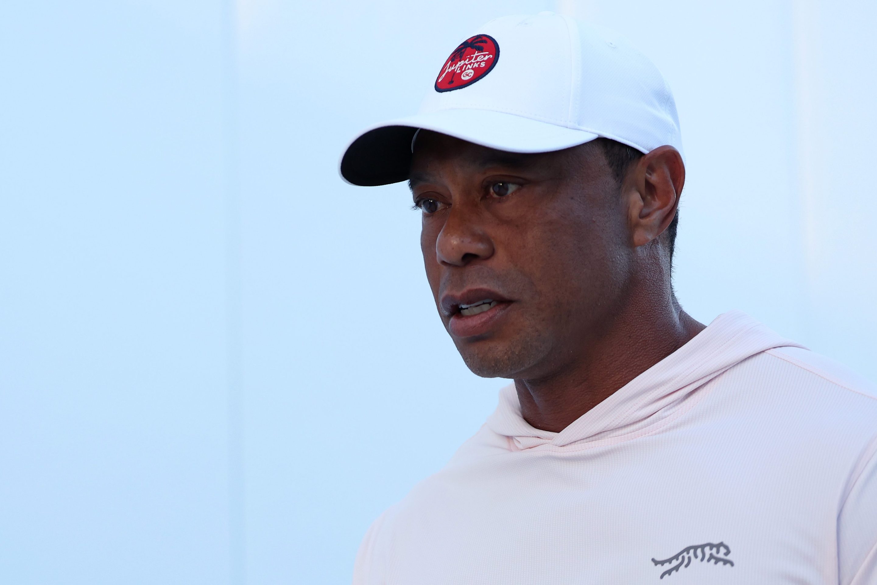 Tiger Woods of Jupiter Links Golf Club arrives before the match against the Los Angeles Golf Club at SoFi Center on March 23, 2026 in Palm Beach Gardens, Florida. He's wearing a white hoodie and a white baseball hat.