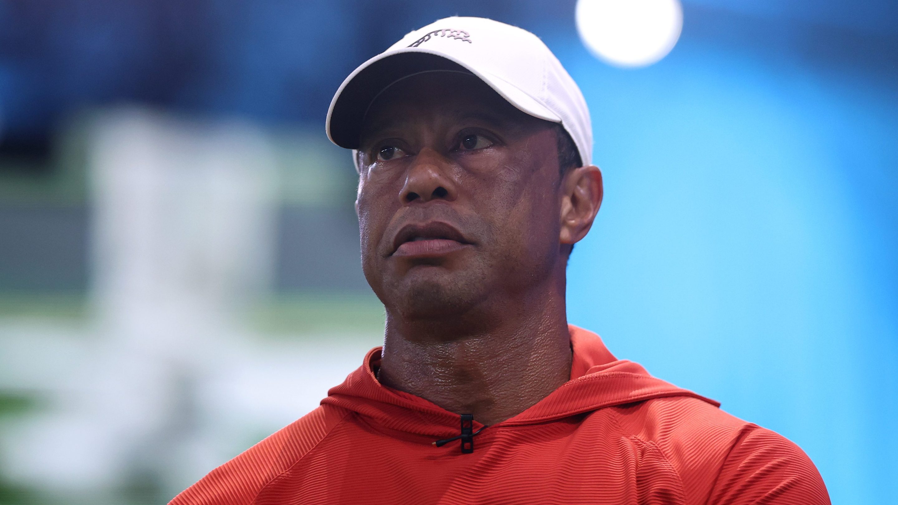 Tiger Woods of Jupiter Links Golf Club looks on before the match against the Los Angeles Golf Club at SoFi Center on March 23, 2026 in Palm Beach Gardens, Florida. He's wearing a red hoodie and a white baseball hat.