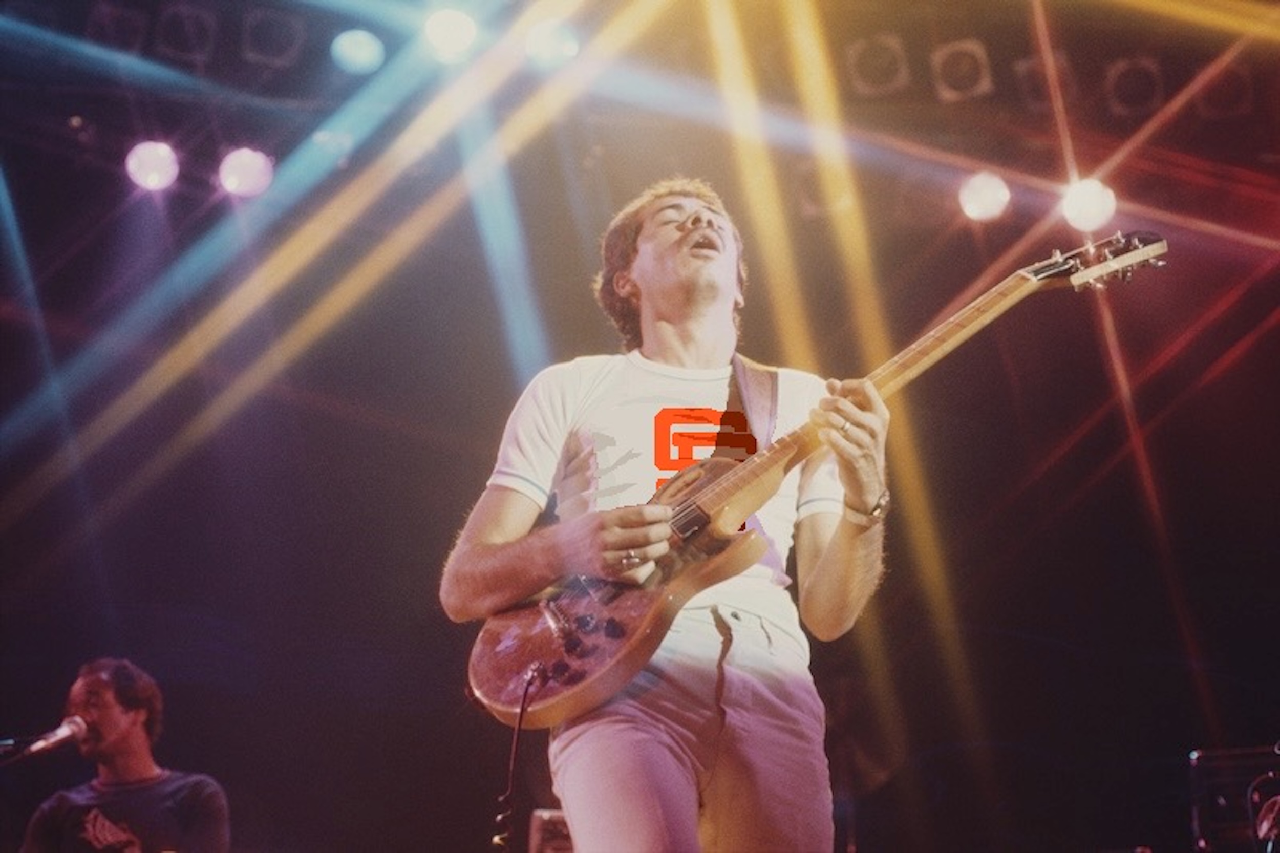 Carlos Santana plays guitar on stage, with the Giants logo drawn onto his t-shirt.
