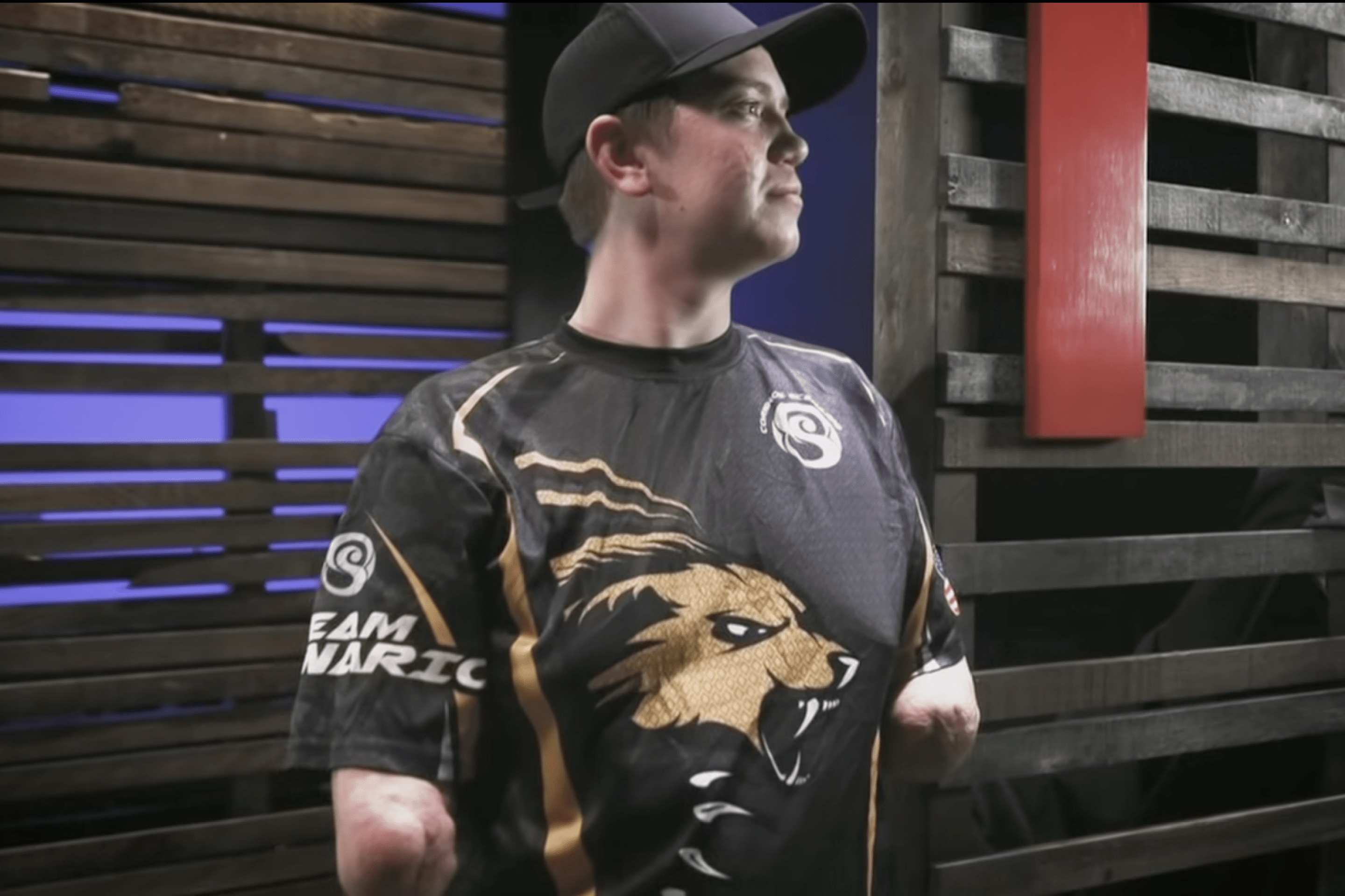 A screenshot of Dalton Webber from a video package done of him by ESPN. In the photo, he is wearing a black sports jersey and a black baseball hat.