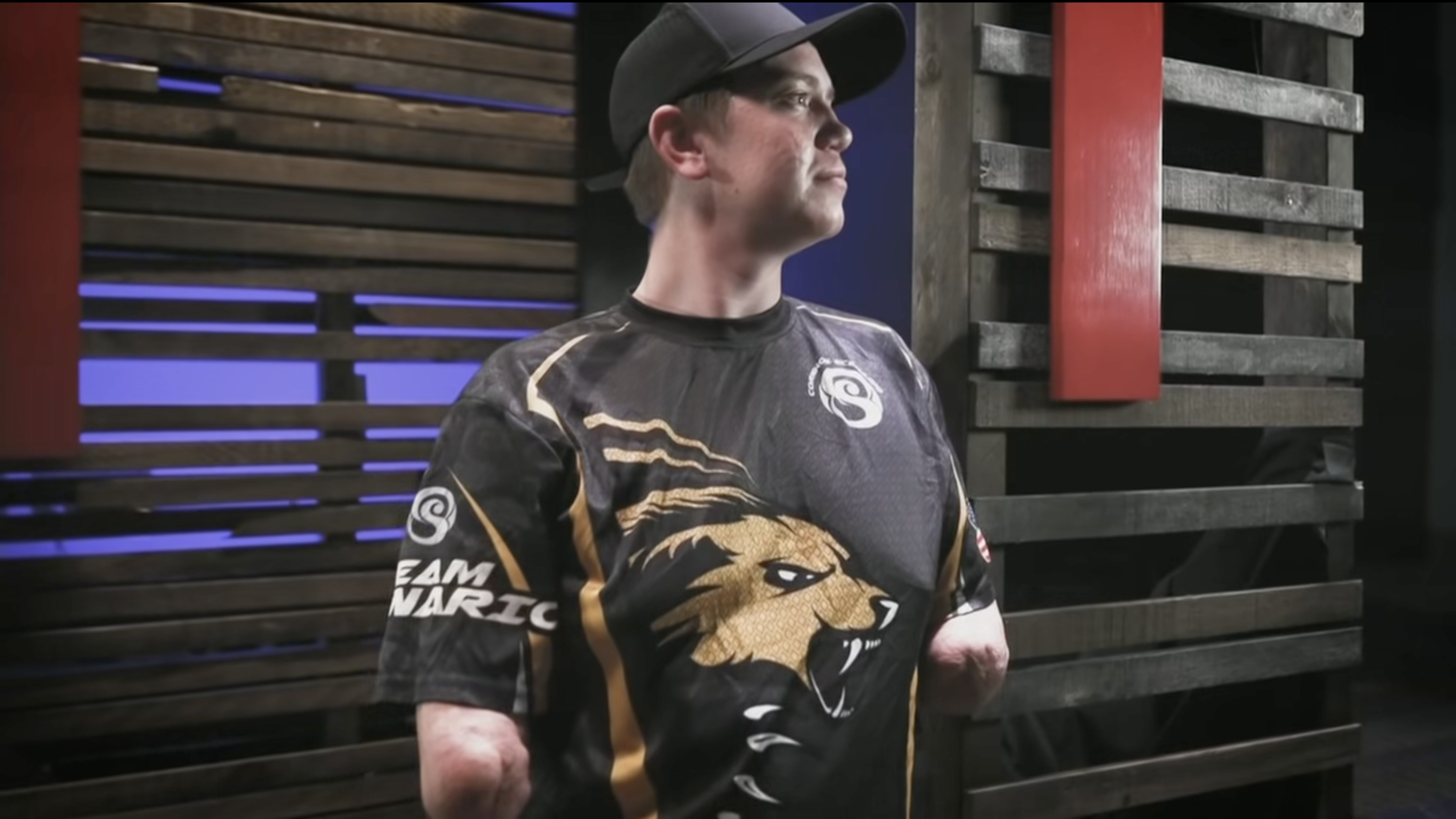 A screenshot of Dalton Webber from a video package done of him by ESPN. In the photo, he is wearing a black sports jersey and a black baseball hat.