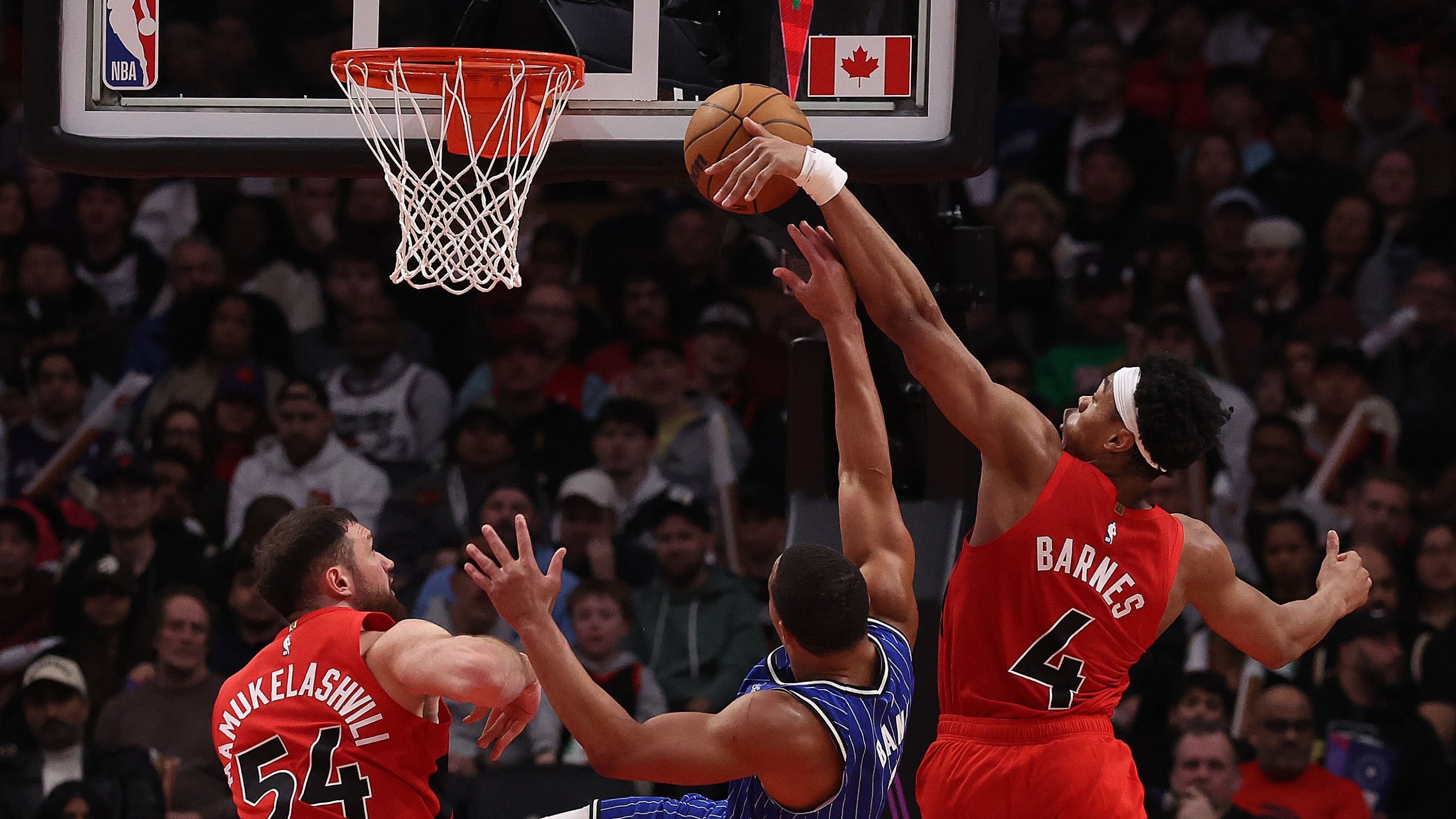 Forward Scottie Barnes #4 of the Toronto Raptors blocks guard Desmond Bane #3 of the Orlando Magic and forward Sandro Mamukelashvili #54 of the Toronto Raptors as the Toronto Raptors beat the Orlando Magic 139-87 in a game that included a 31-0 run by the Toronto Raptors at Scotiabank Arena in Toronto. March 29, 2026.