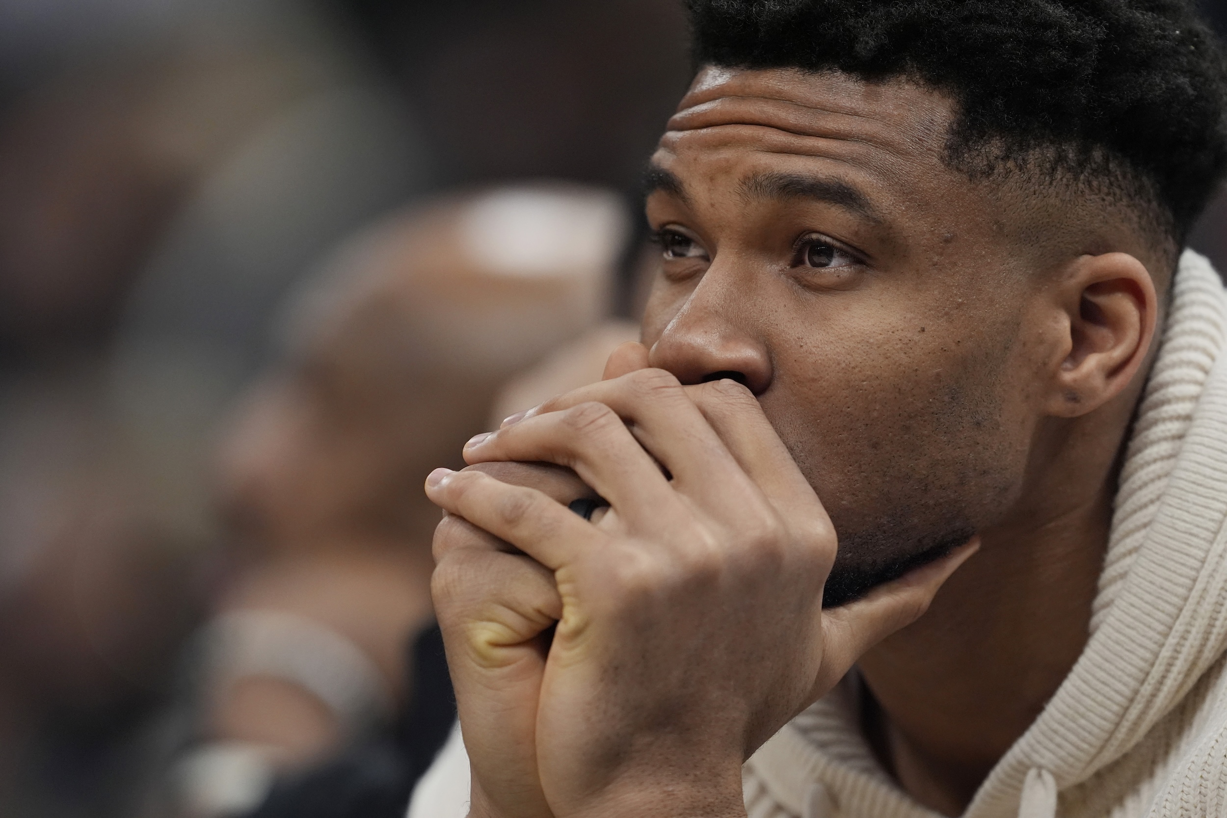 Giannis Antetokounmpo sits on the sideline, in street clothes.
