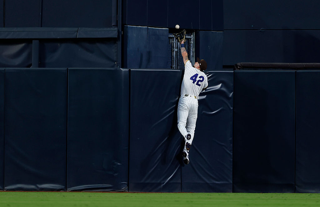 jackson merrill stretches up above the outfield fence to steal a home run ball