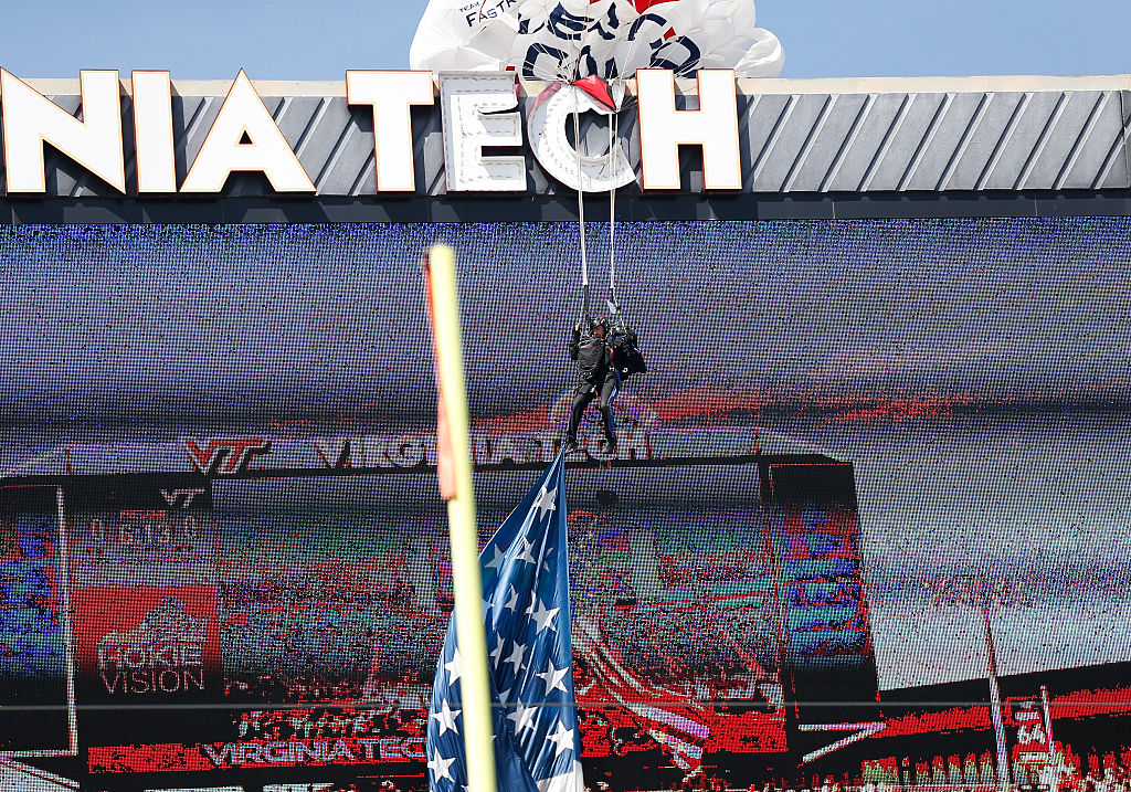 A paratrooper who crashed into the jumbotron at the Virginia Tech football stadium dangles from his parachute above the crowd before the spring football game on April April 18, 2026, at Lane Stadium