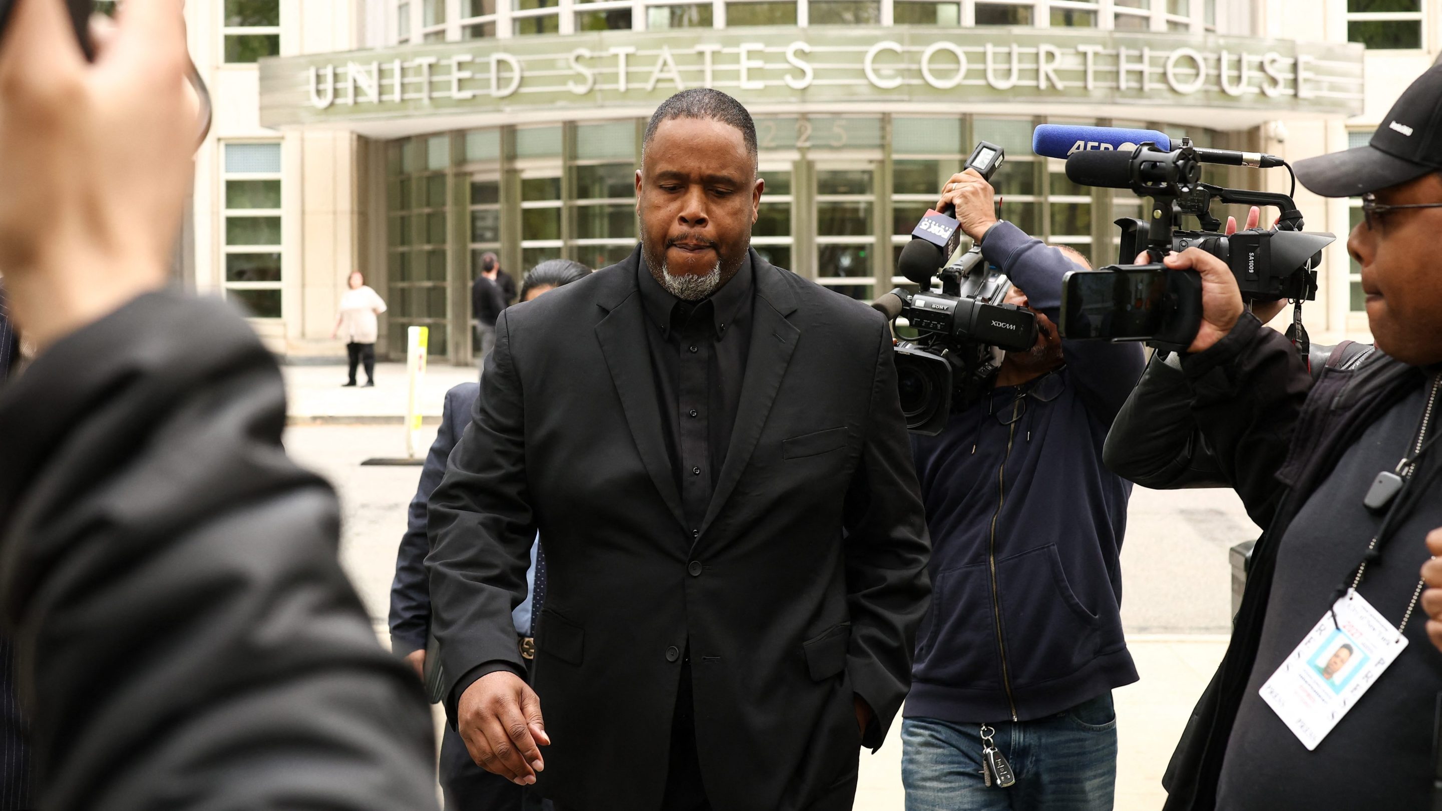 Former NBA player and assistant coach Damon Jones leaves the federal courthouse in Brooklyn, New York on April 28, 2026. He wore a black suit and has several news photographers around him.