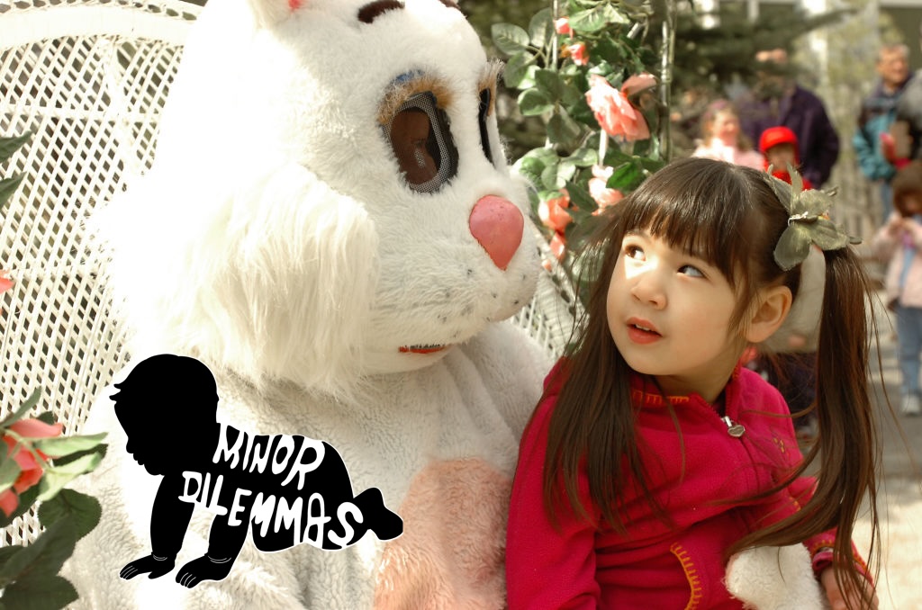 A little girl sits on the lap of the easter bunny and looks skeptical