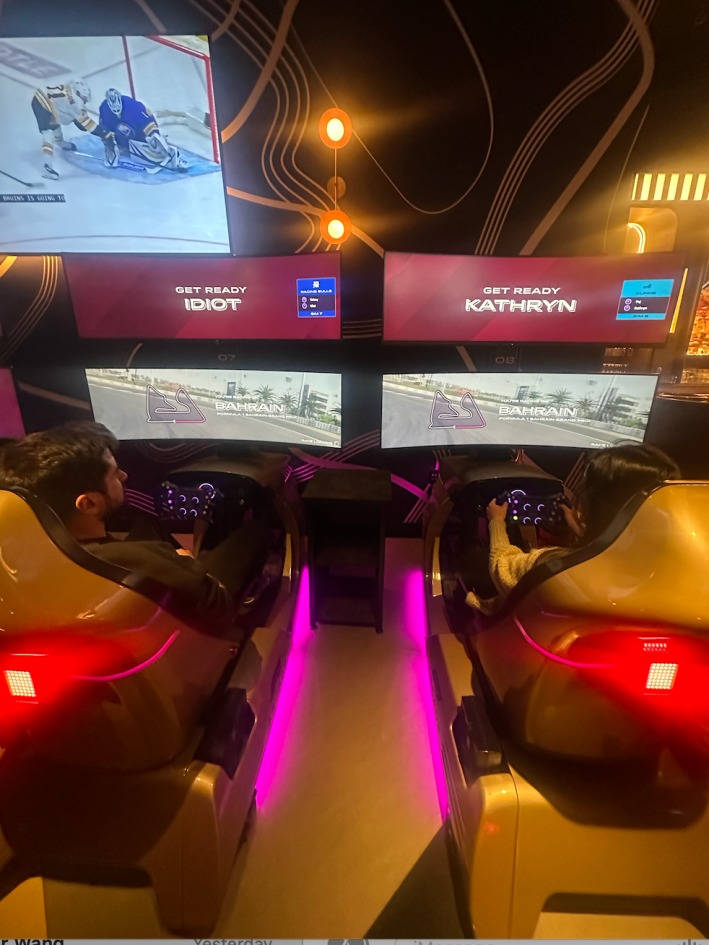 luis and kathryn in their simulators. screens reading "get ready Kathryn" and "get ready idiot"