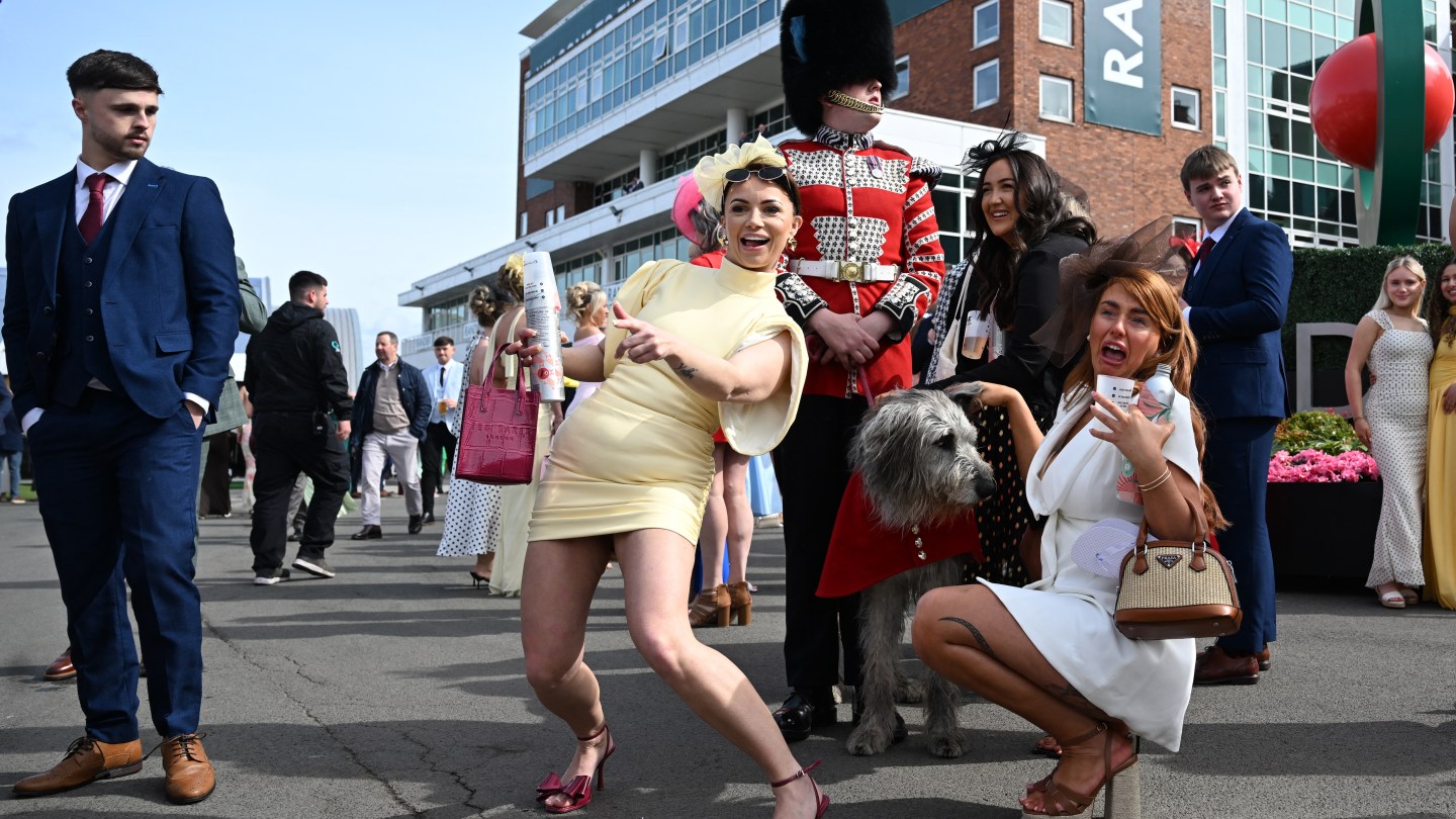 TOPSHOT - Racegoers pose for a picture with Irish Guards' mascot "Seamus" on Ladies Day, day two of the Grand National Festival horse race.