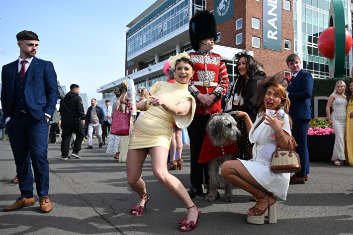 TOPSHOT - Racegoers pose for a picture with Irish Guards' mascot "Seamus" on Ladies Day, day two of the Grand National Festival horse race.