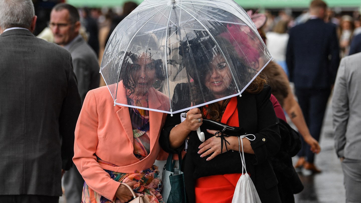 Racegoers try to avoid the rain on the final day of the Grand National Festival horse race meeting.