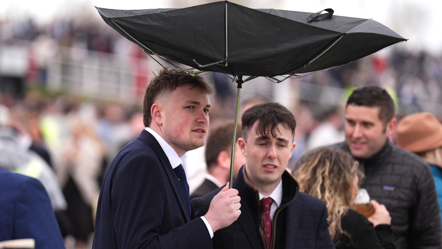 A racegoer holds an umbrella which is inside out on Grand National Day of the Randox Grand National Festival 2026 at Aintree Racecourse.